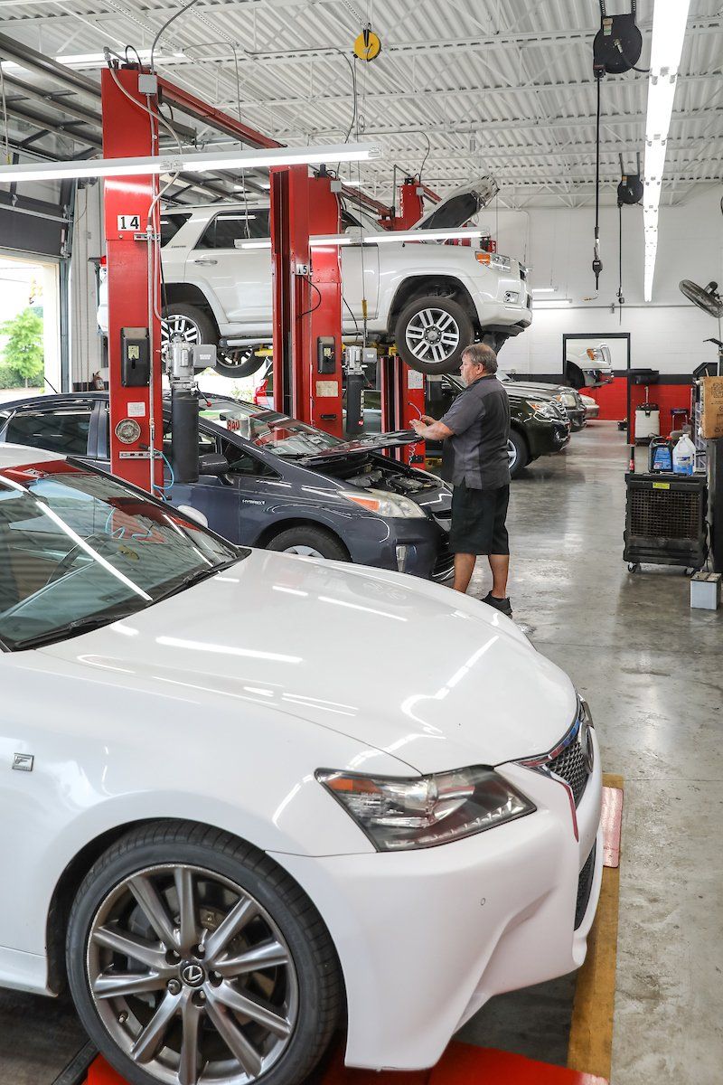 A man is working on a white car in a garage.