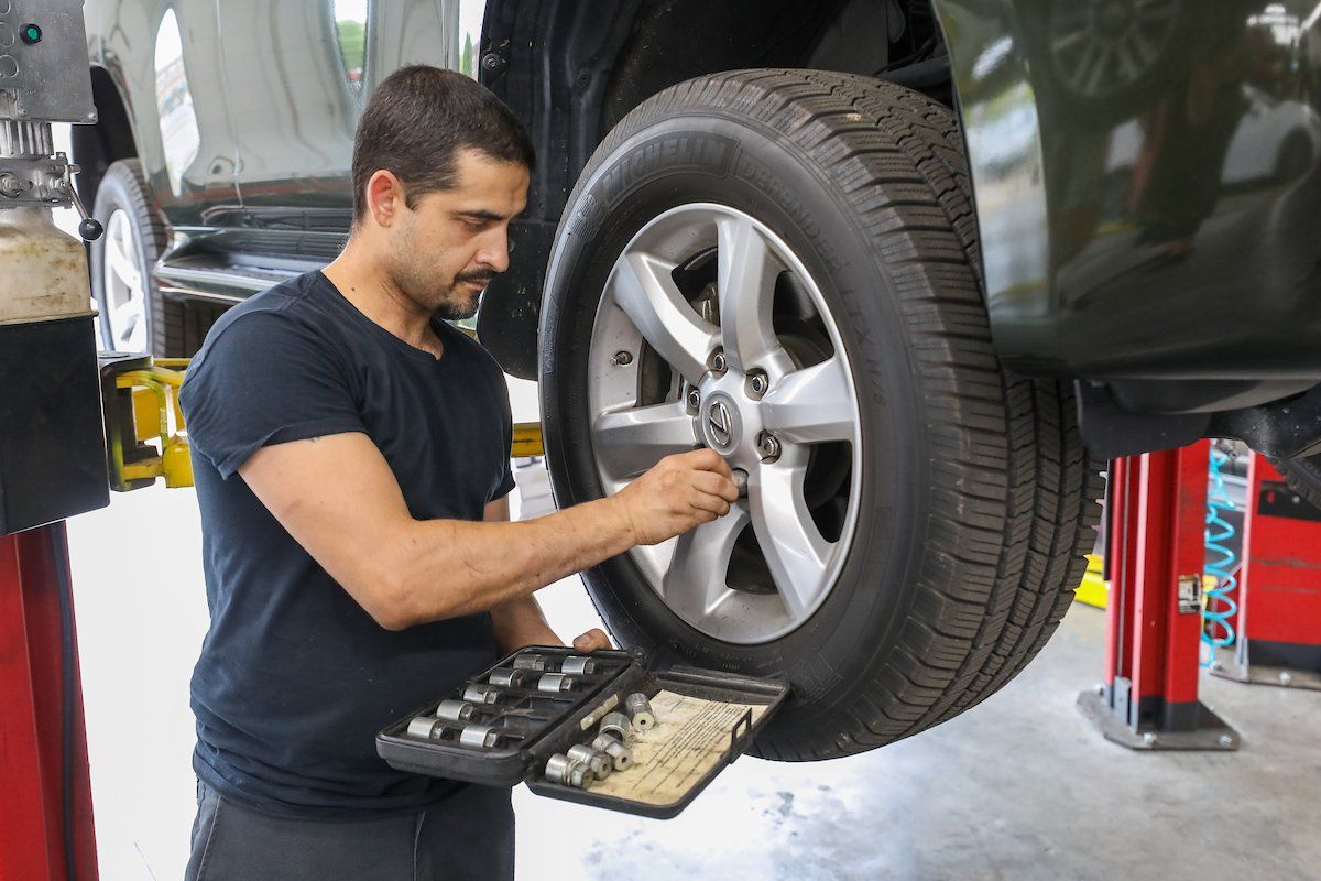 A man is working on a car wheel in a garage.
