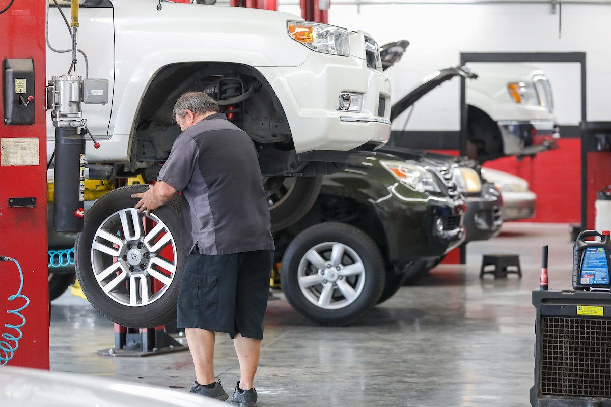 A man is changing a tire on a car in a garage.