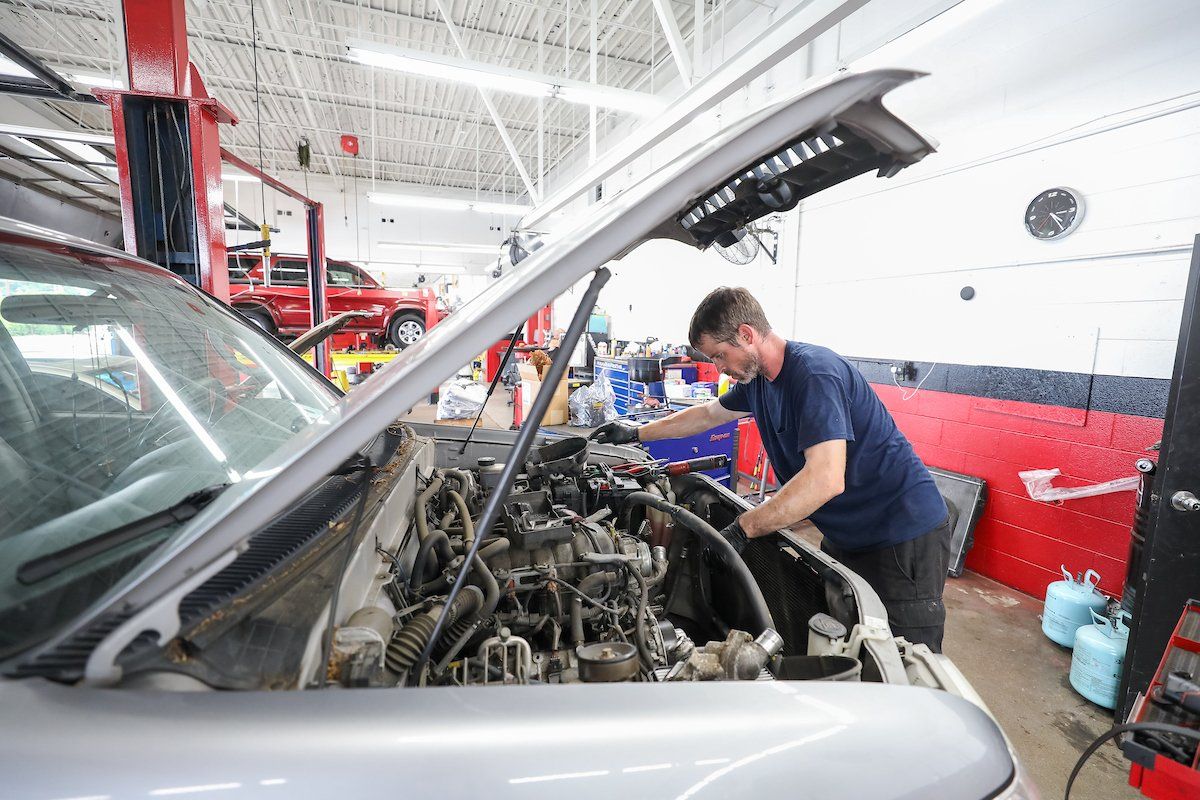 A man is working on the engine of a car in a garage.