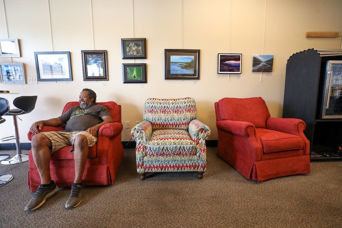 A man is sitting in a red chair in a living room.
