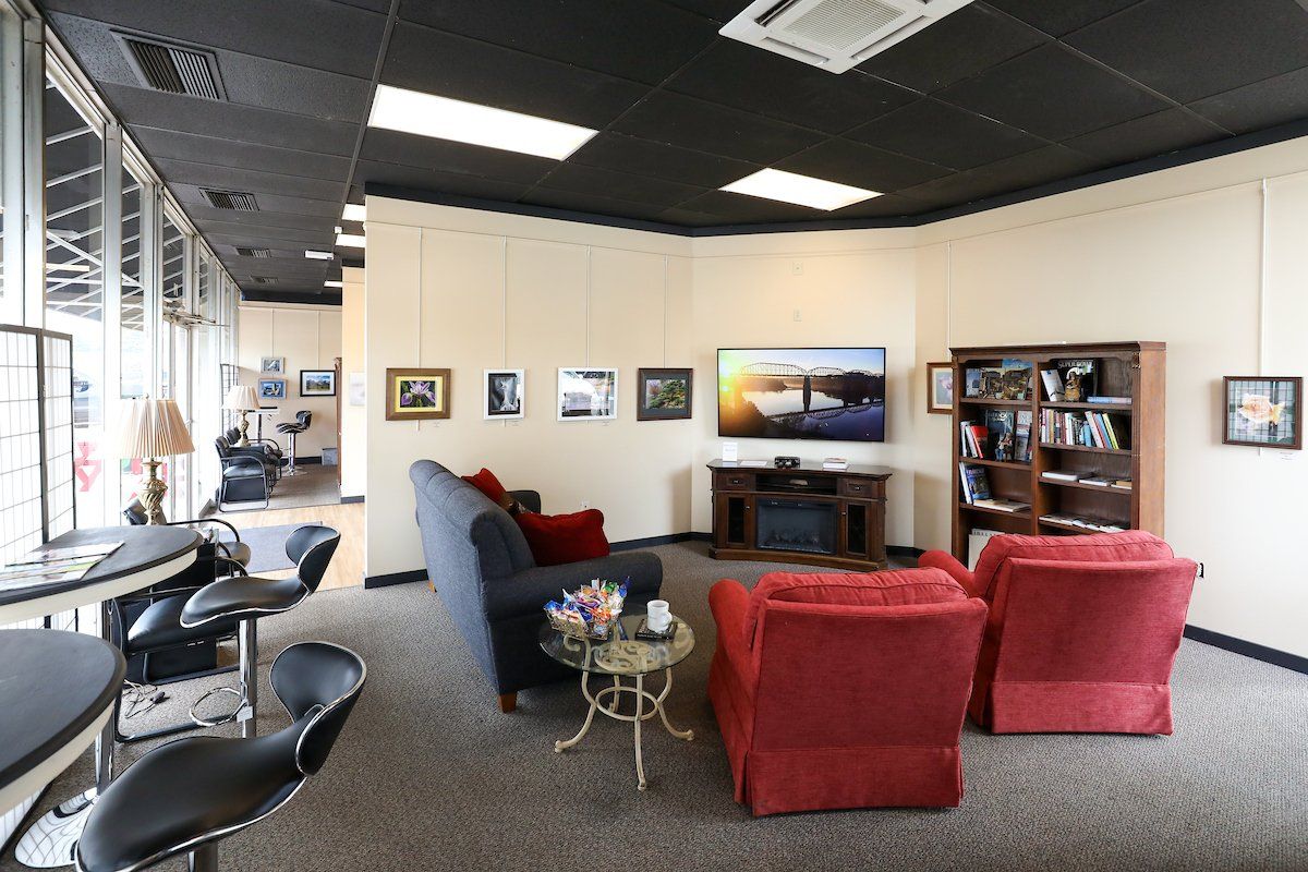 A living room with a couch , two chairs , a table and a television.