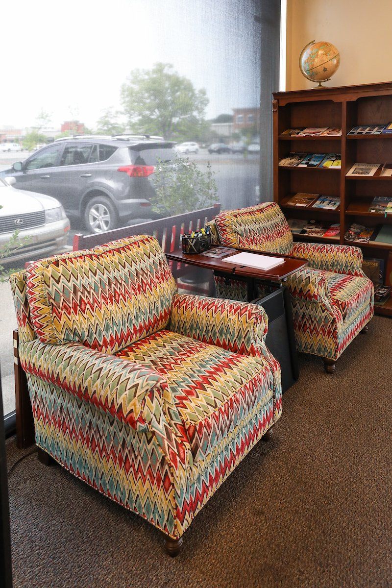 Two chairs and a table in a room with a globe on the wall.