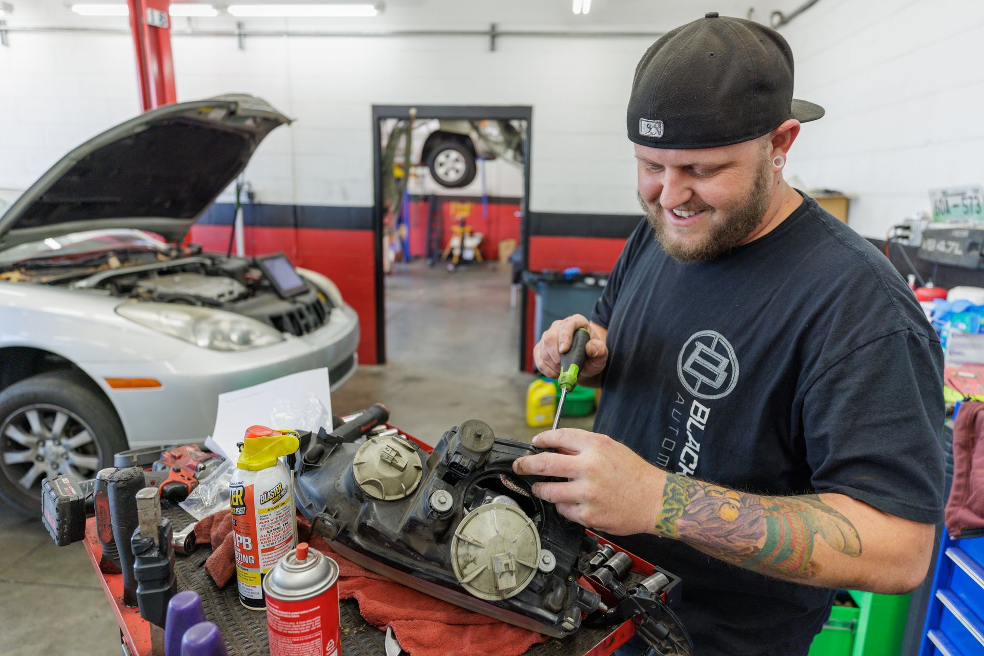 A man is working on a car headlight in a garage.