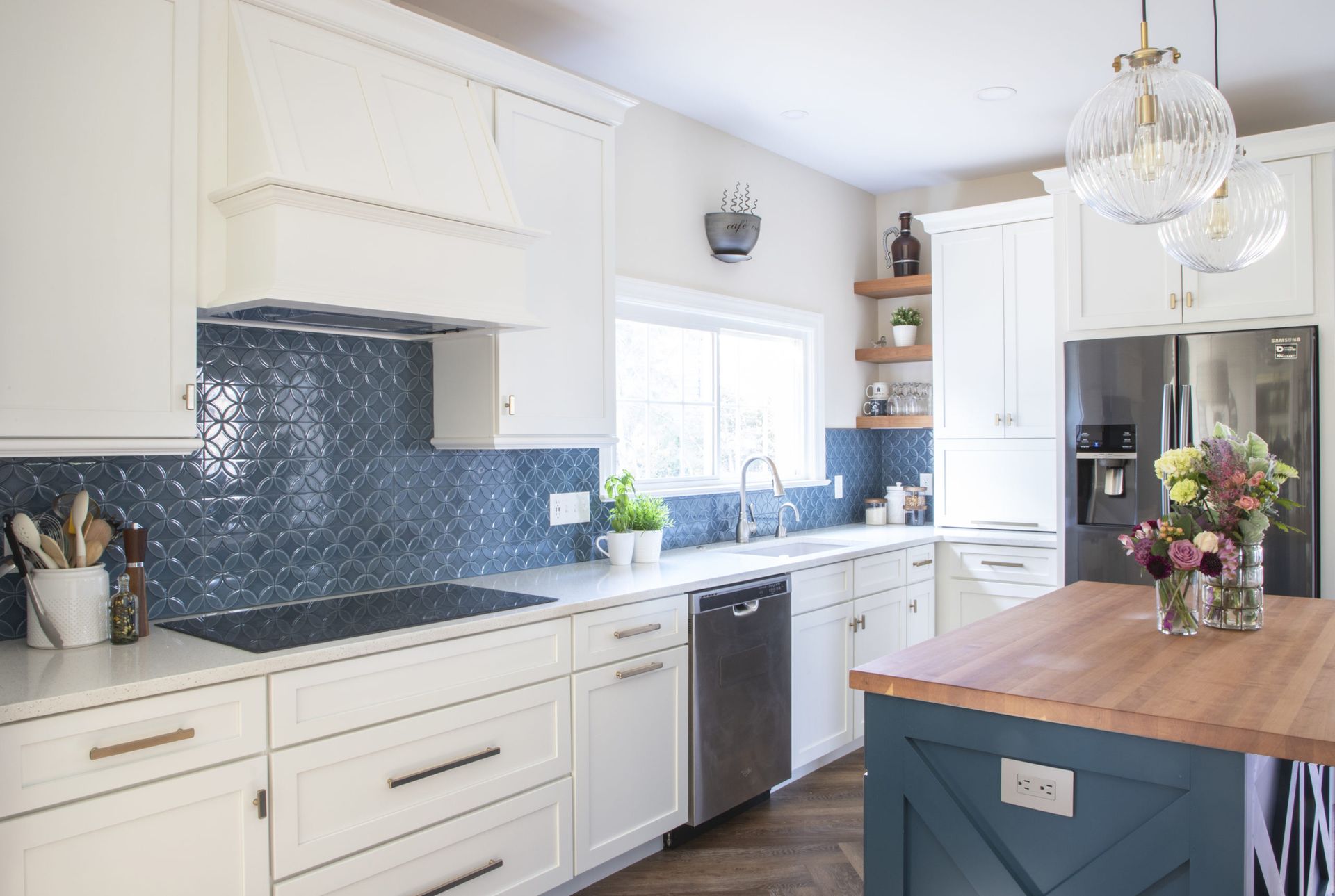A kitchen with white cabinets and blue tiles has a large island in the middle of the kitchen.