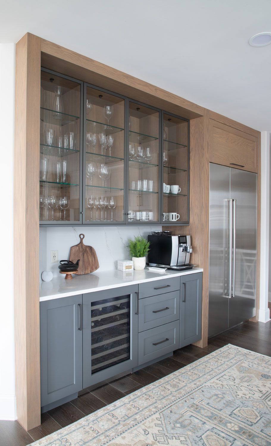 A kitchen with gray cabinets , stainless steel appliances , and a wine cooler.
