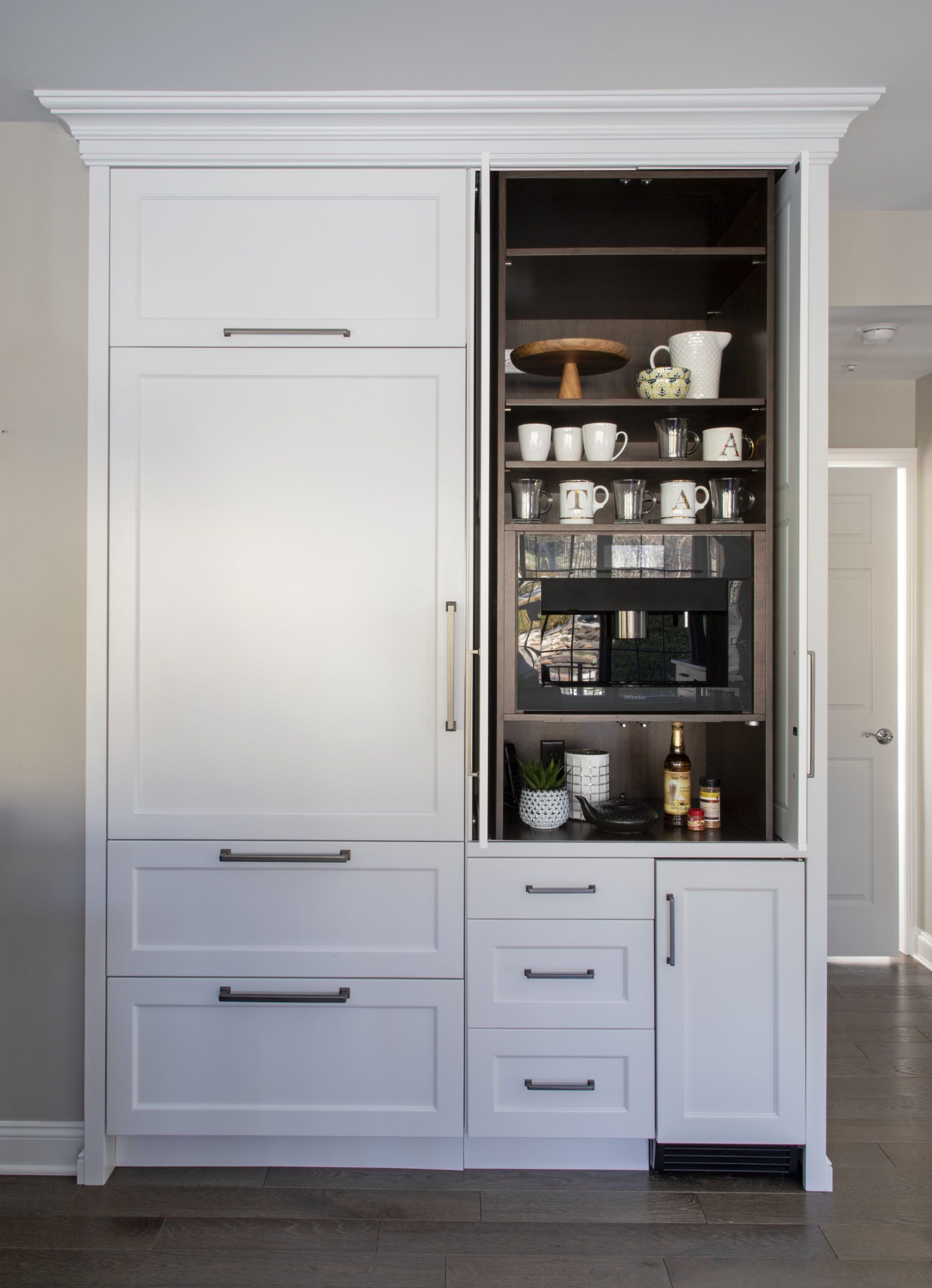 A kitchen with white cabinets and drawers and a bar