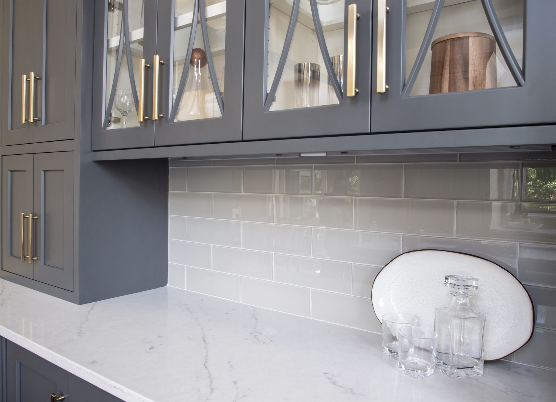 A kitchen with gray cabinets and a white counter top.