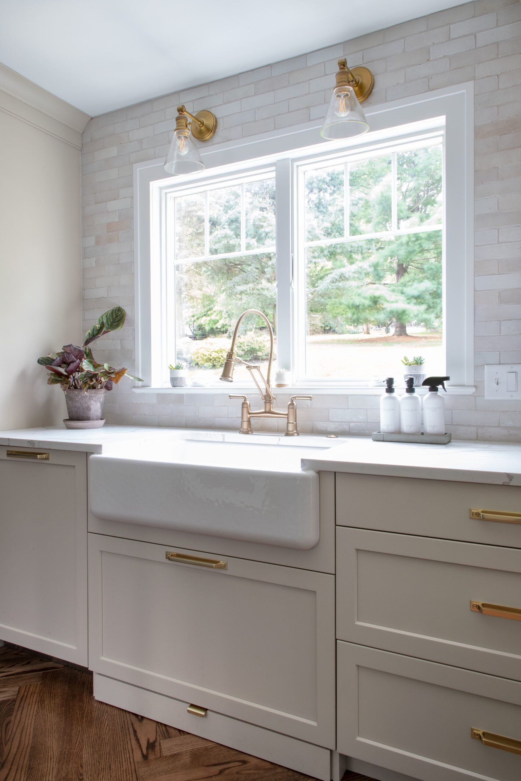 A kitchen with a sink , cabinets , and a window.