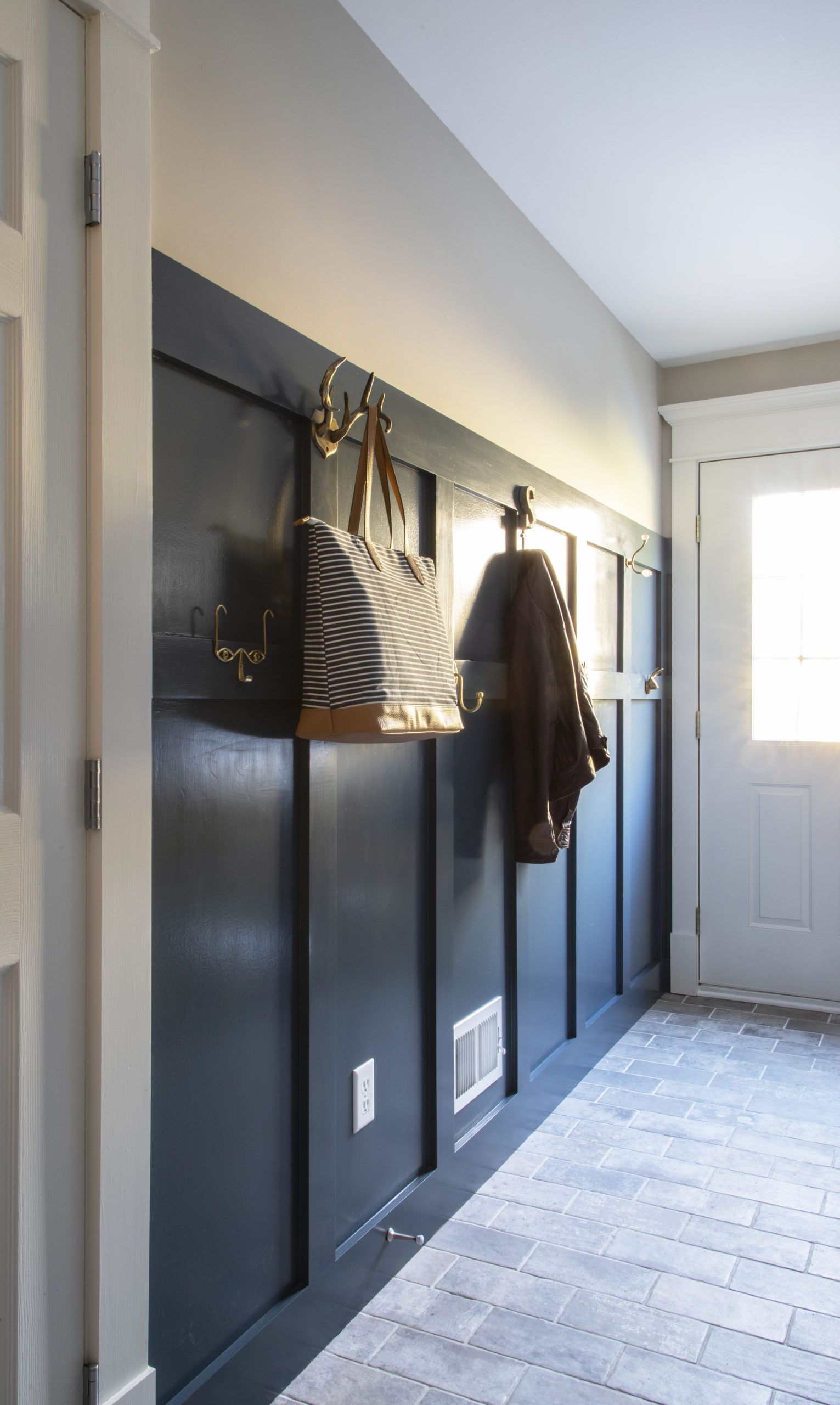 A hallway with a coat and a purse hanging on the wall.