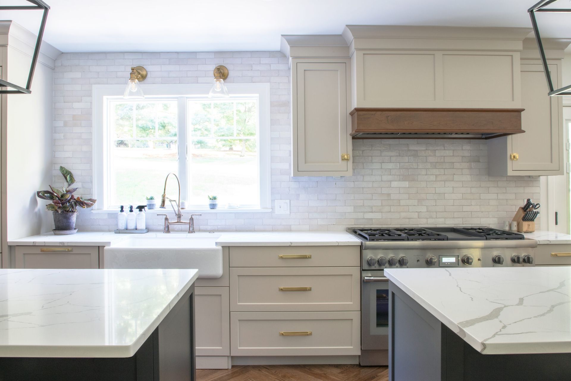 A kitchen with white cabinets , a stove , a sink , and a window.