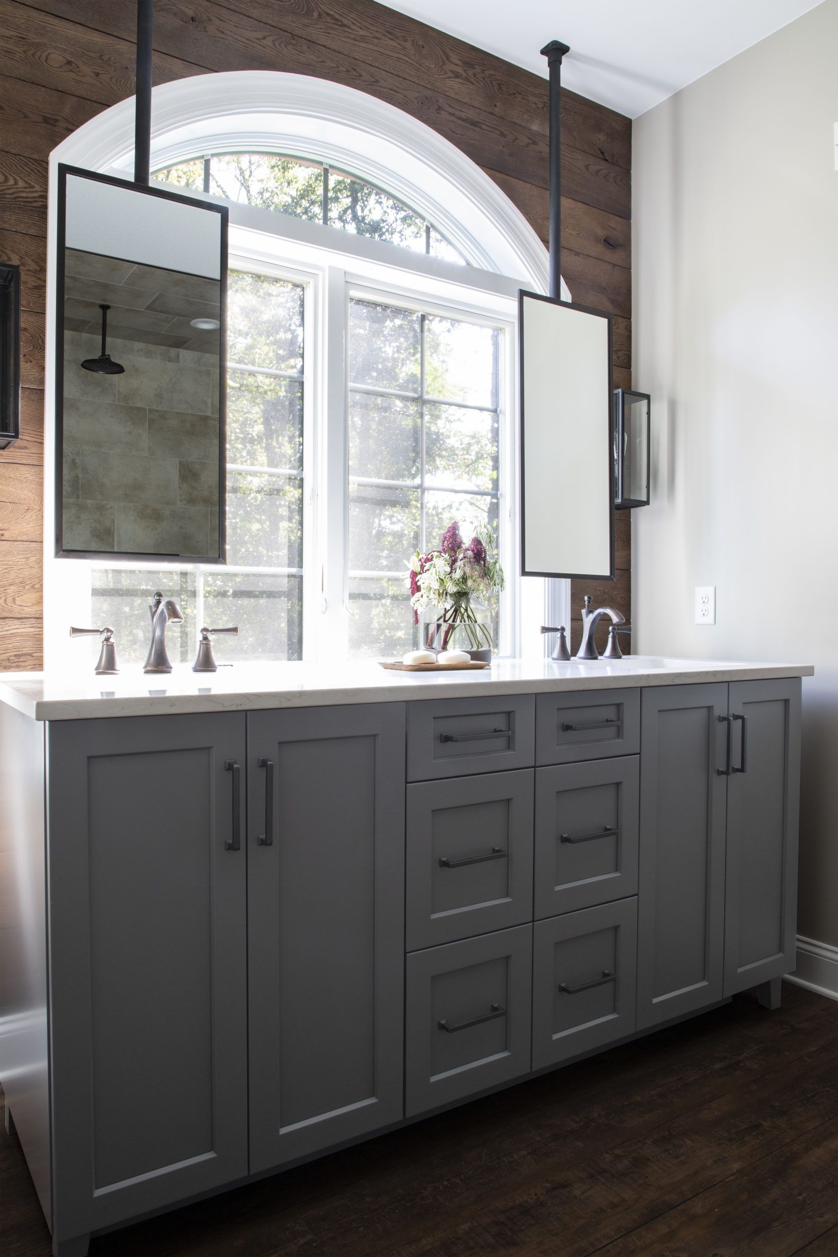 A bathroom with two sinks and two mirrors hanging from the ceiling