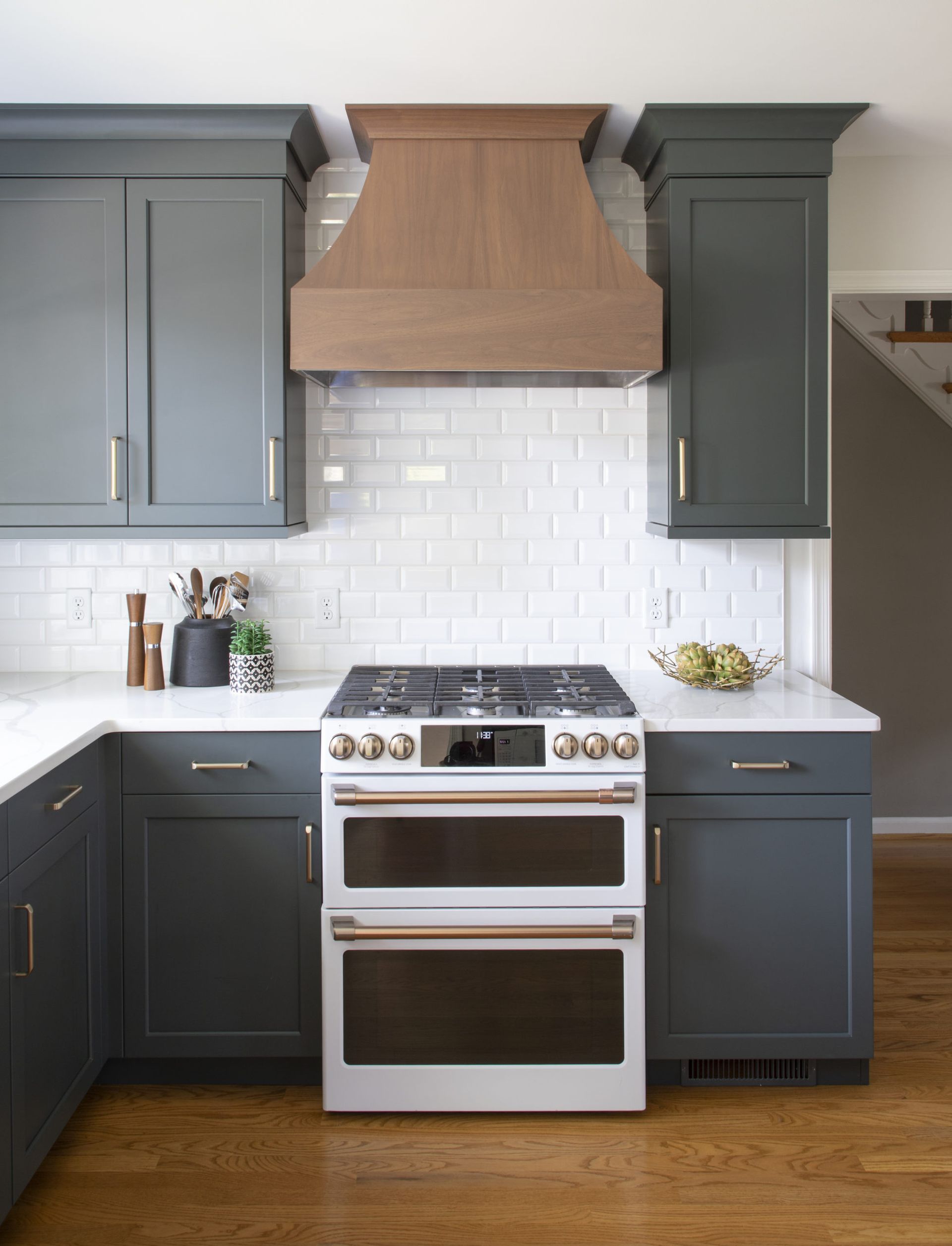 A kitchen with a white stove and a wooden hood above it.