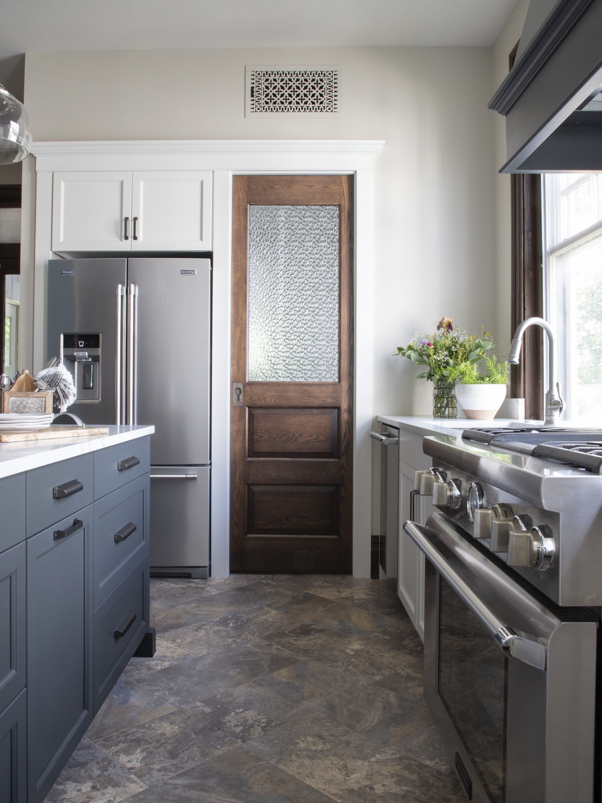 A kitchen with stainless steel appliances and a wooden door