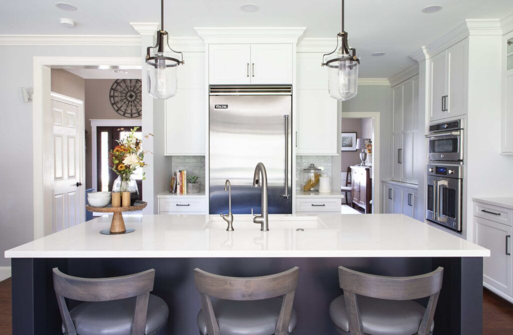 A kitchen with white cabinets , stainless steel appliances and a large island.