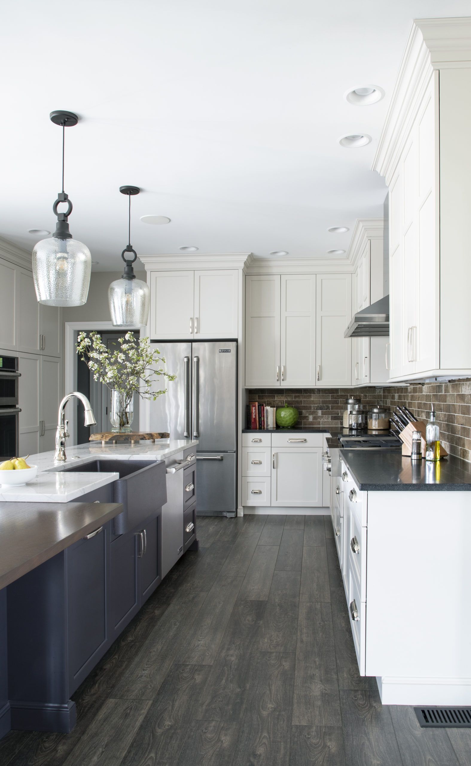 A kitchen with white cabinets , black counter tops , and stainless steel appliances.
