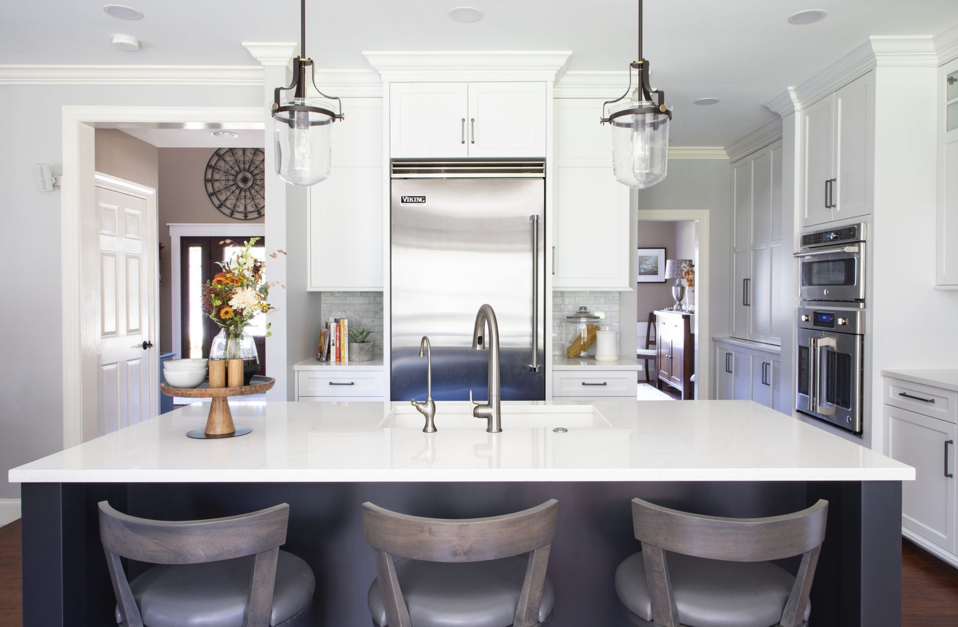 A kitchen with white cabinets , stainless steel appliances , a sink , and a large island.
