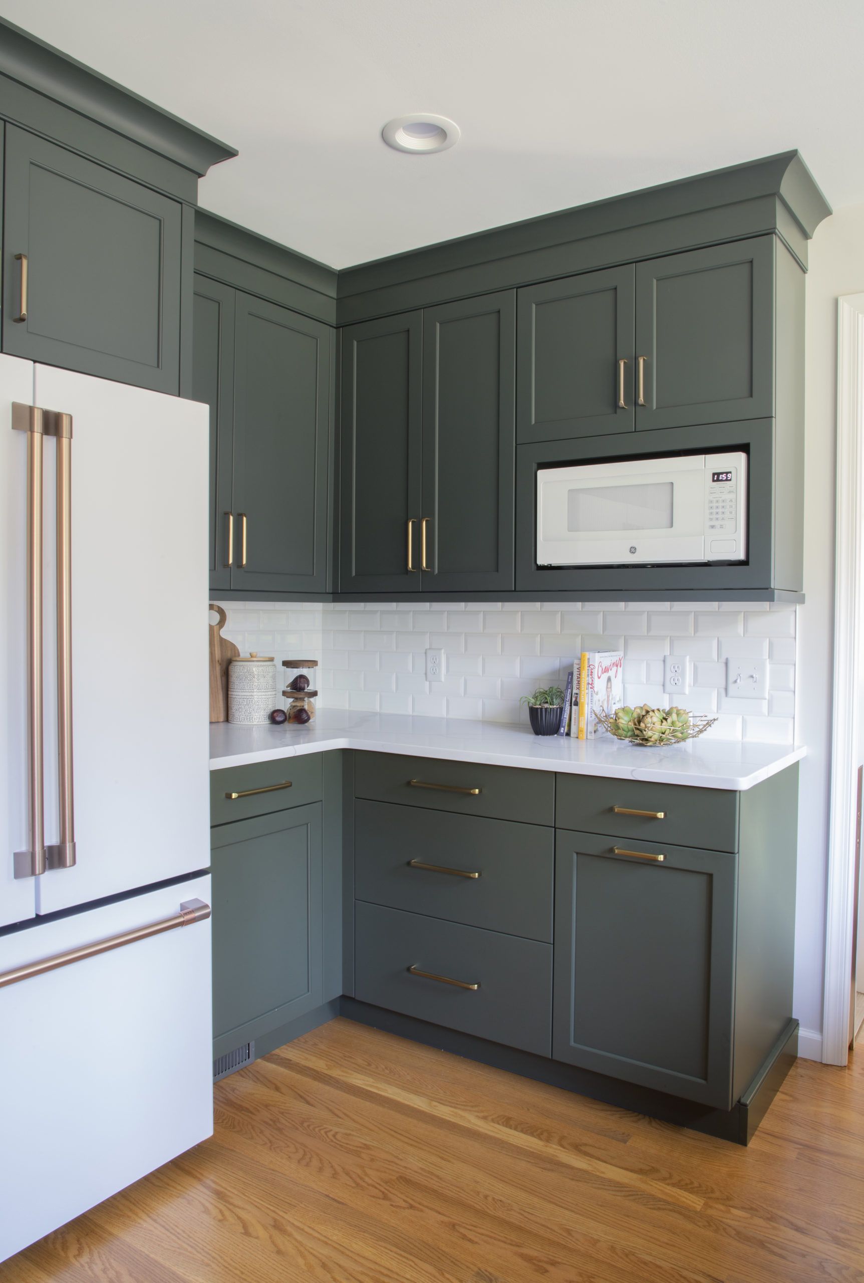 A kitchen with green cabinets and a white refrigerator