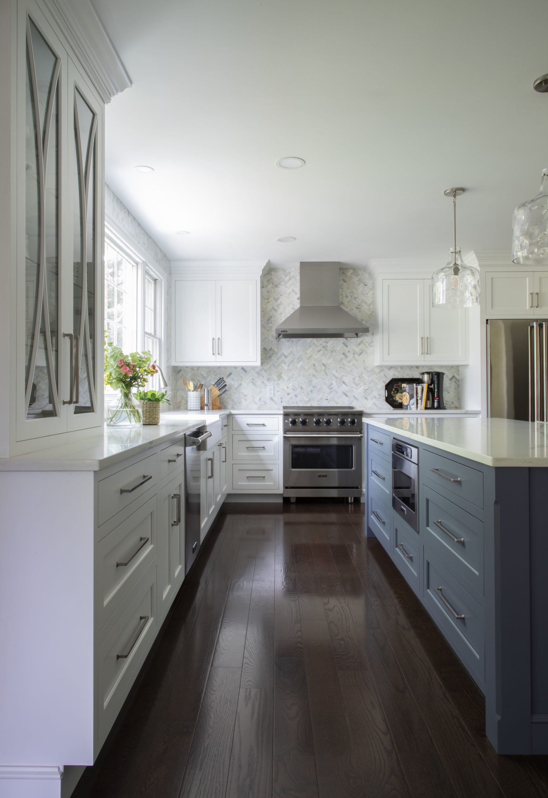 A kitchen with white cabinets , blue cabinets , and stainless steel appliances.