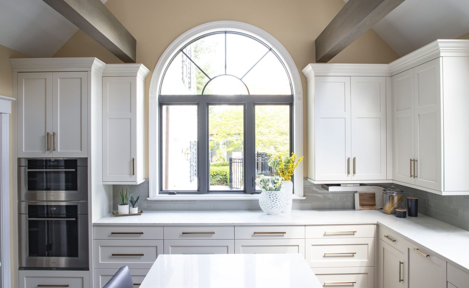 A kitchen with white cabinets , stainless steel appliances , and a large window.