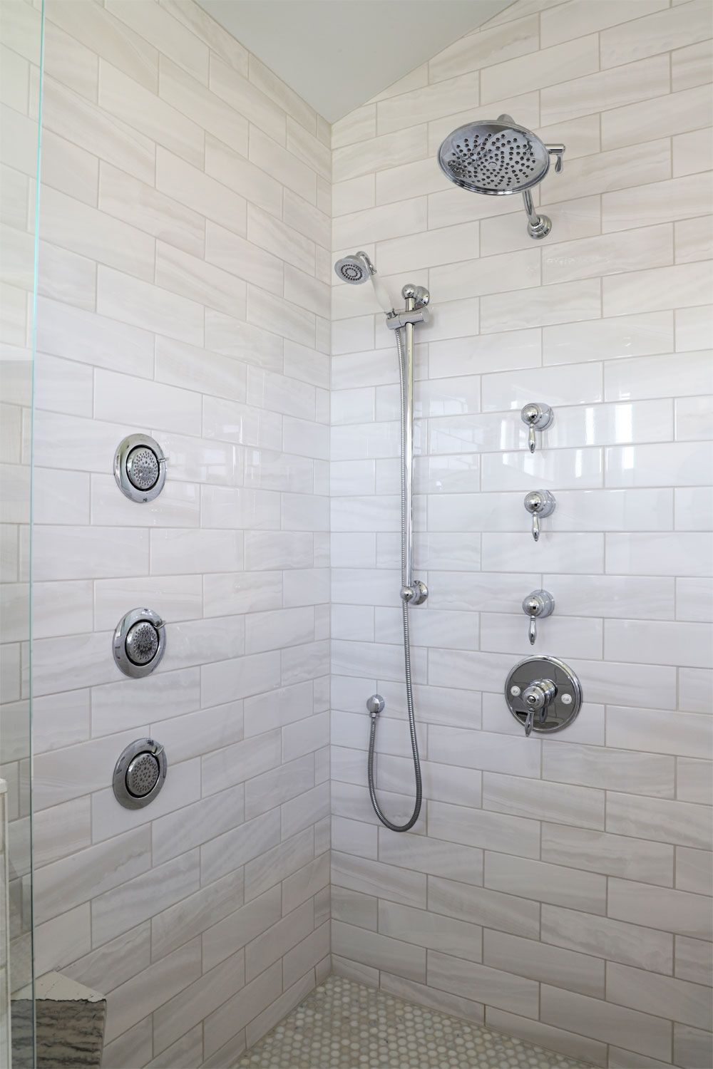 A shower with white tiles and a shower head.