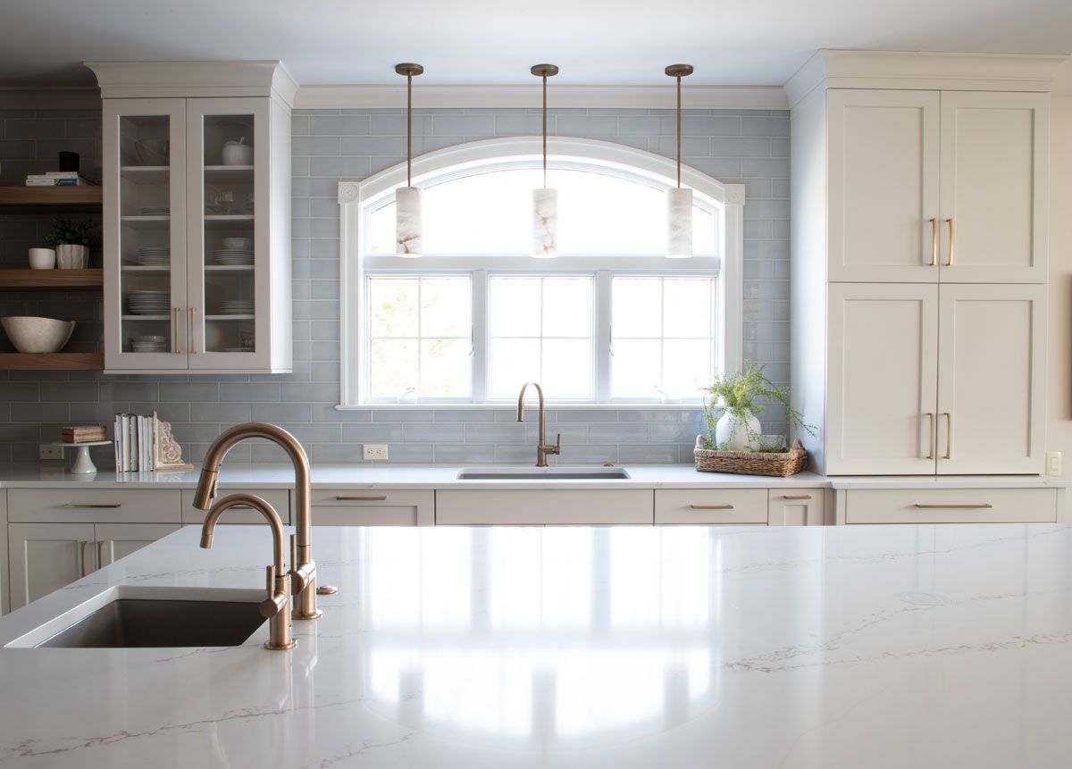 A kitchen with white cabinets , a sink , and a window.