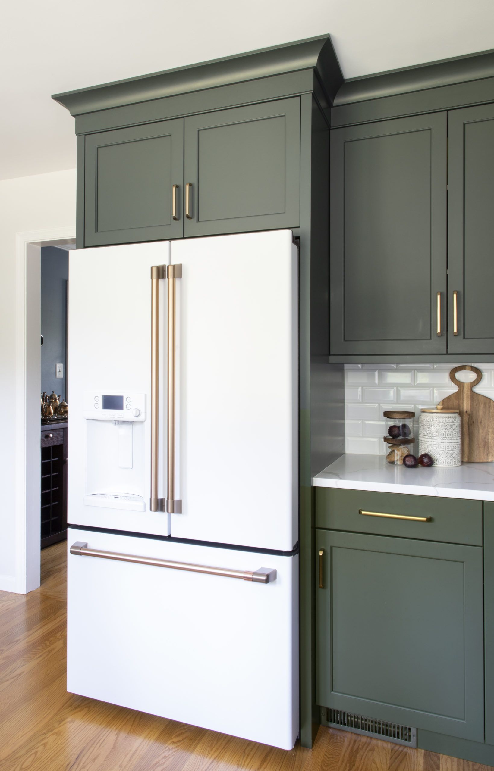 A kitchen with green cabinets and a white refrigerator.