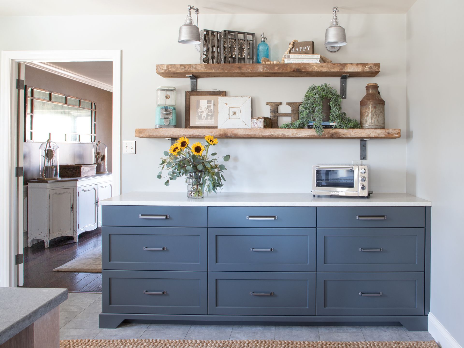 A kitchen with blue cabinets and wooden shelves.