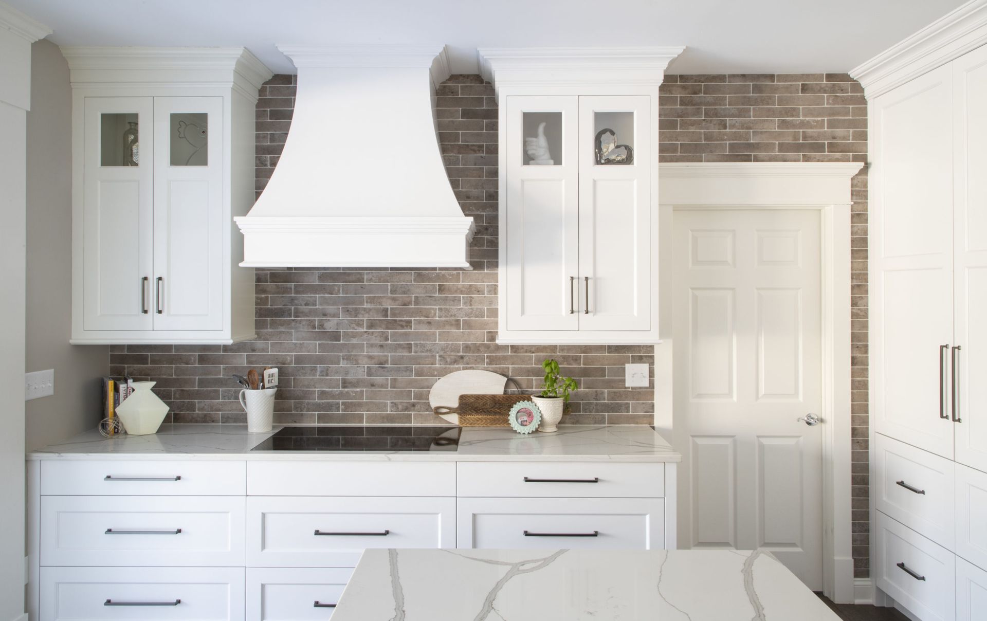 A kitchen with white cabinets and a brick wall.