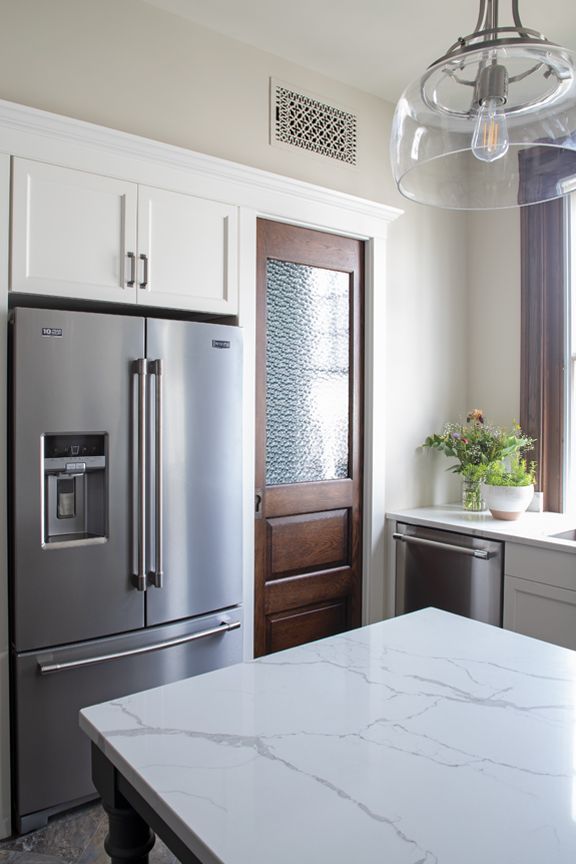 A kitchen with a stainless steel refrigerator and a white counter top.