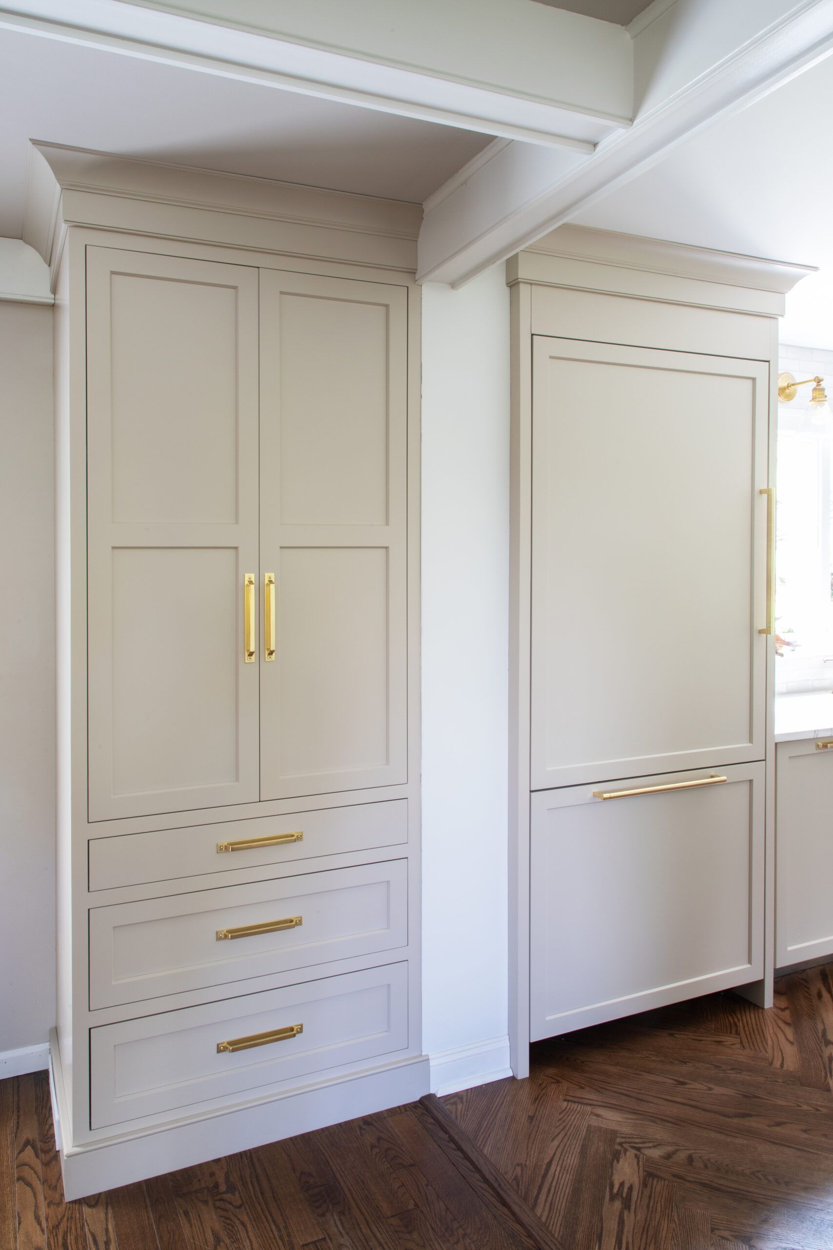 A kitchen with white cabinets , drawers , and a refrigerator.