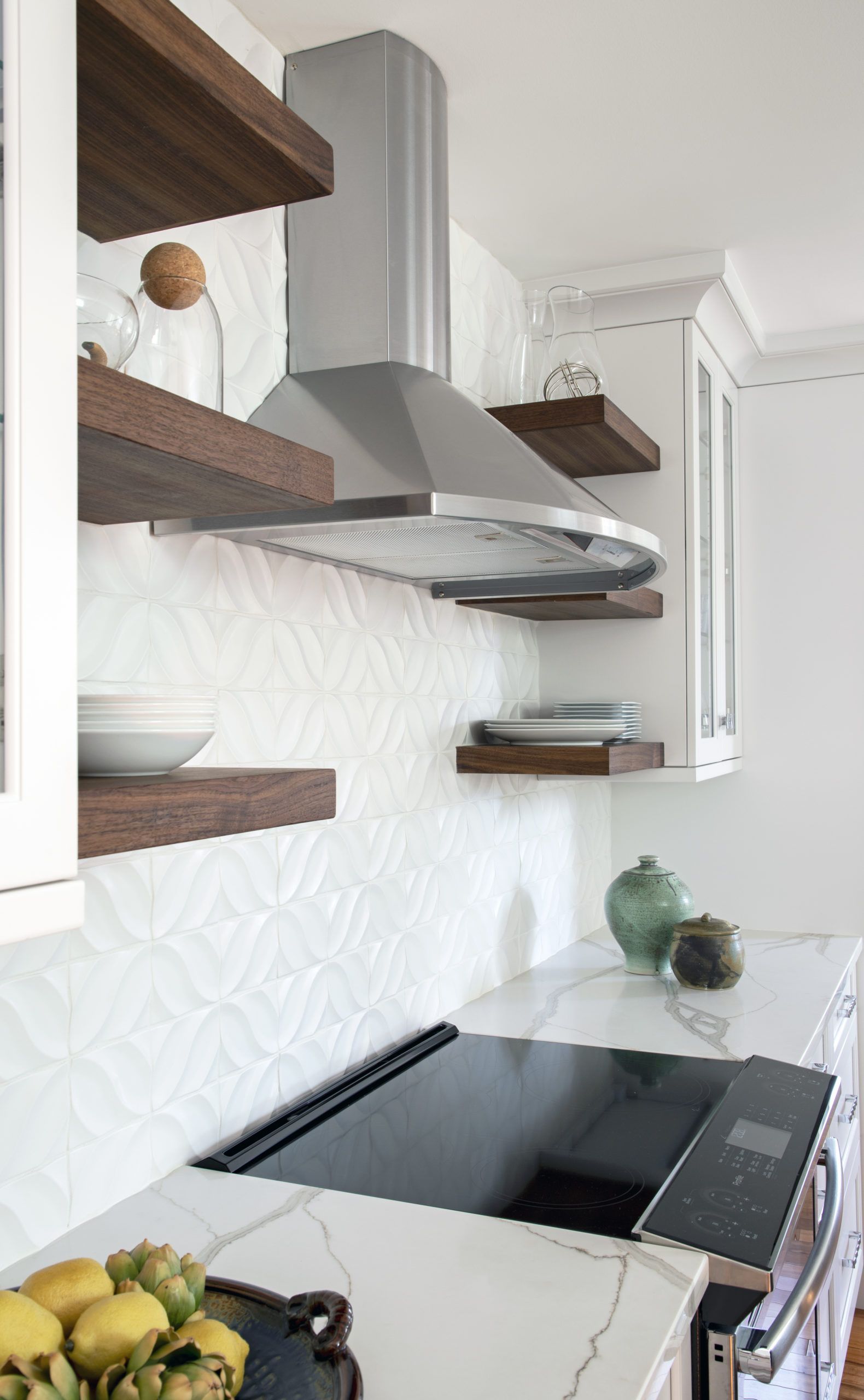 A kitchen with a stove top oven , shelves , and a hood.