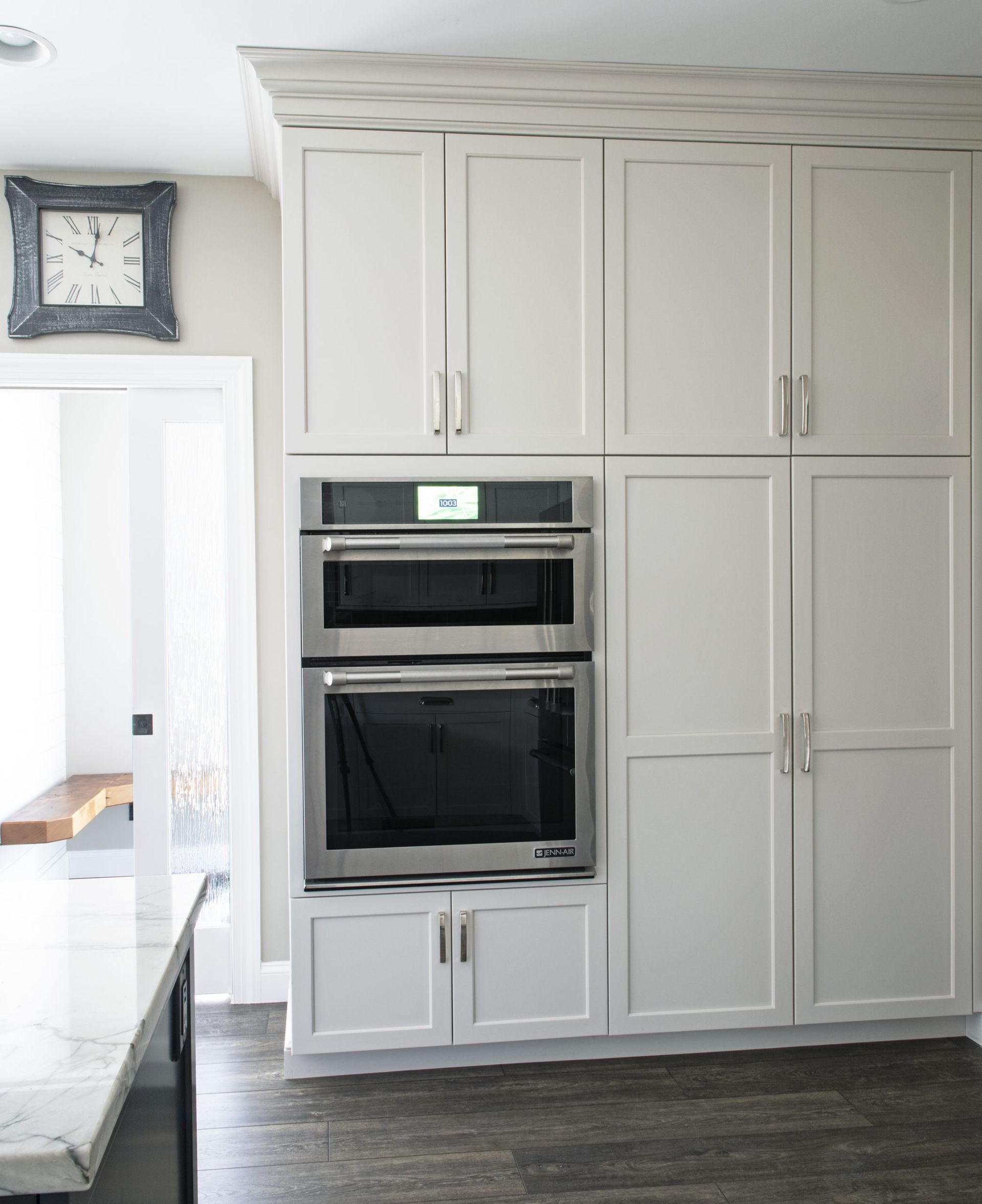 A kitchen with white cabinets and a clock above the oven