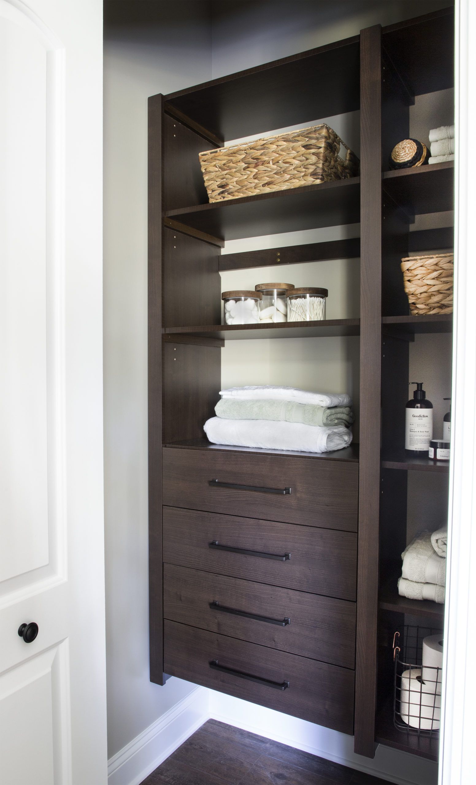 A walk in closet with shelves and drawers filled with towels and baskets.