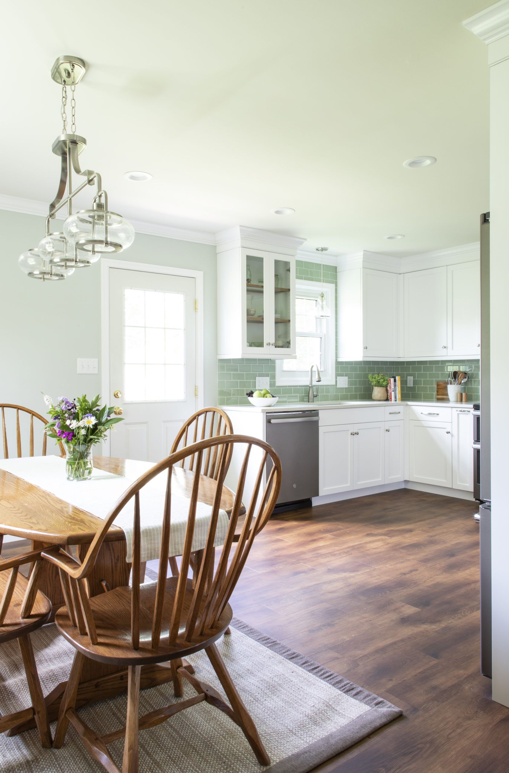 A dining room with a table and chairs and a kitchen in the background.