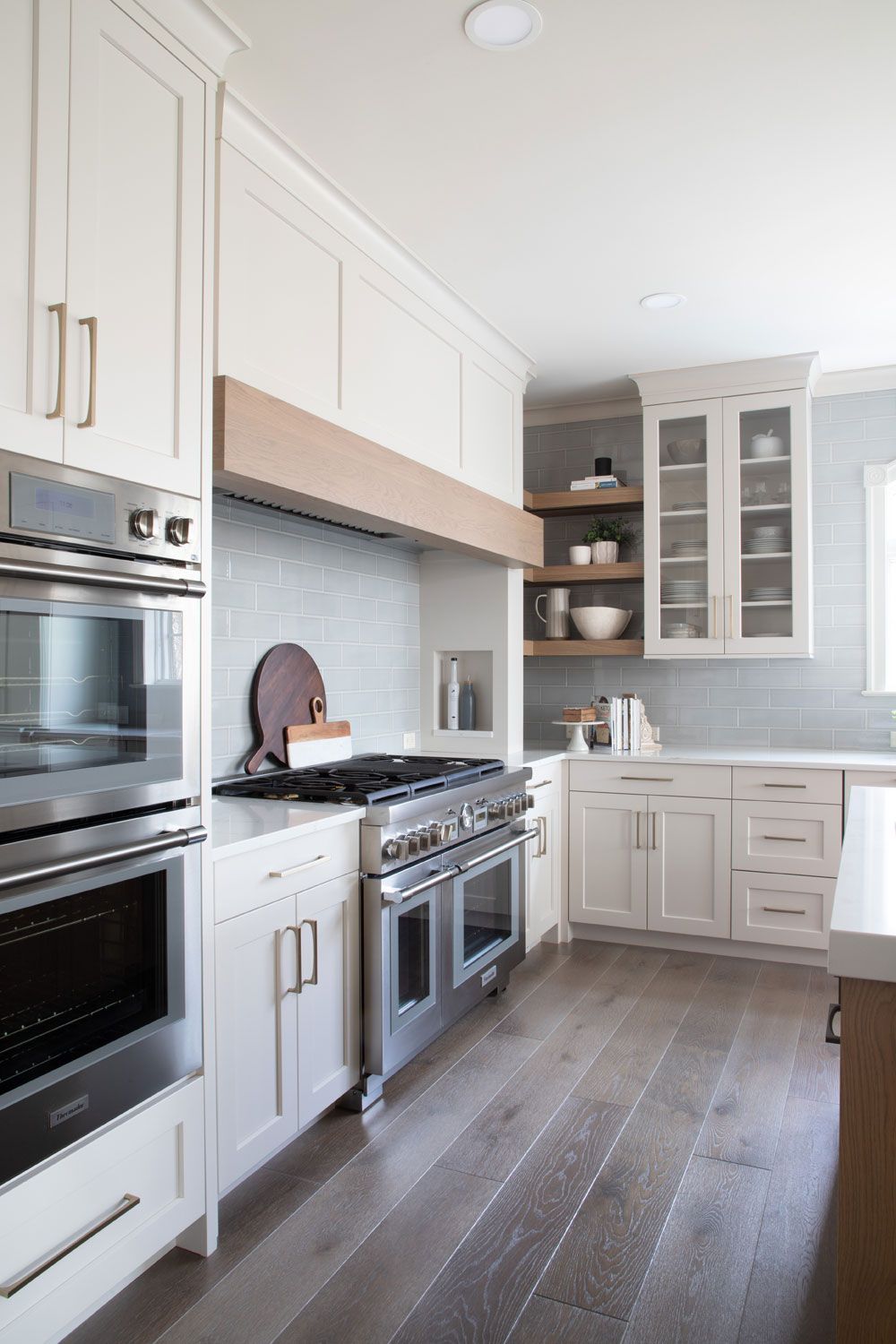 A kitchen with white cabinets , stainless steel appliances , and hardwood floors.