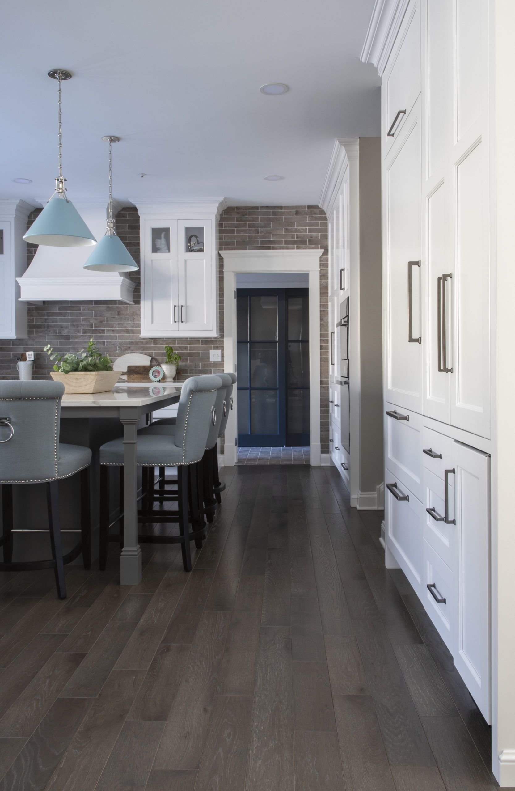A kitchen with white cabinets and dark wood floors