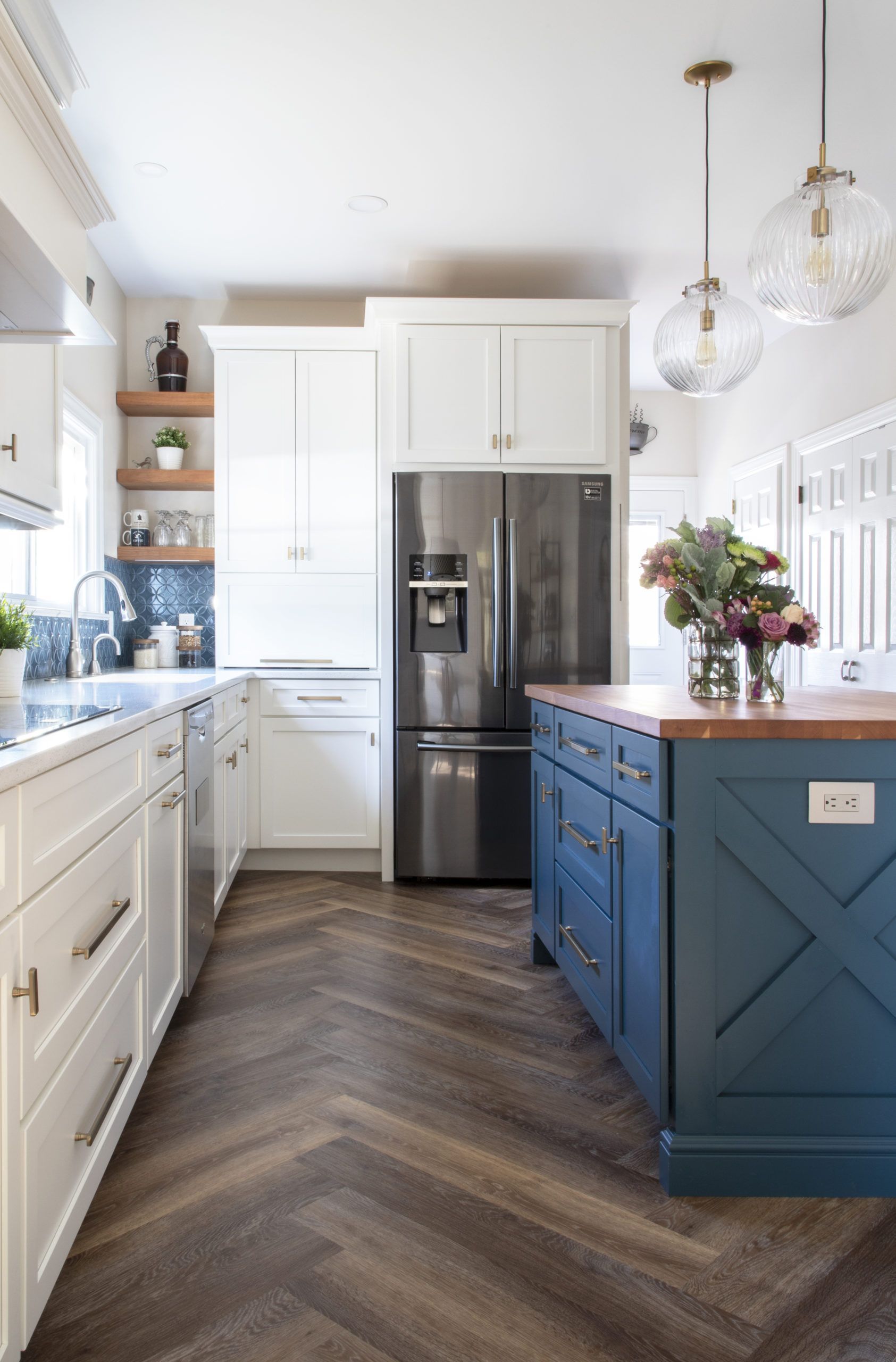 A kitchen with white cabinets , stainless steel appliances , and a blue island.