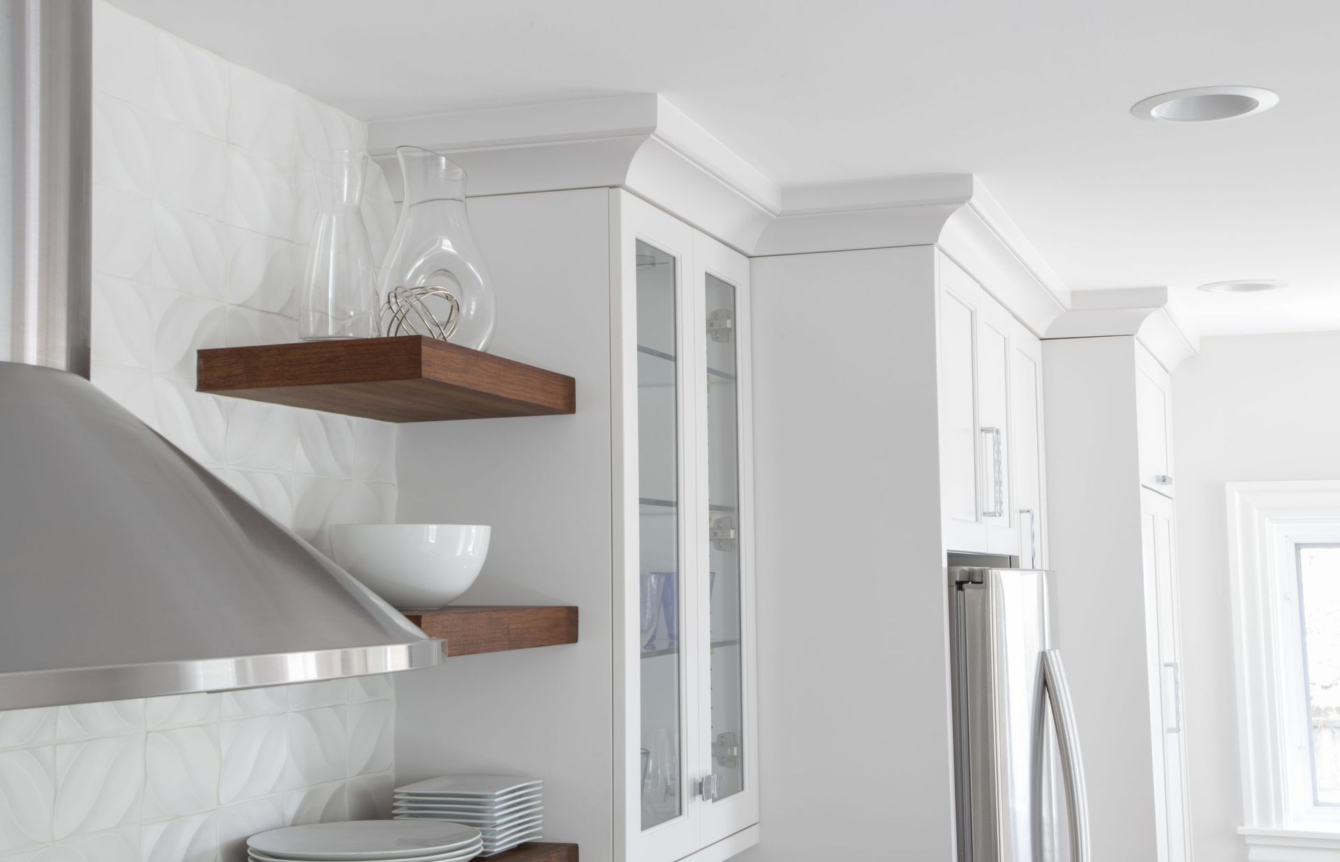 A kitchen with white cabinets and a stainless steel hood