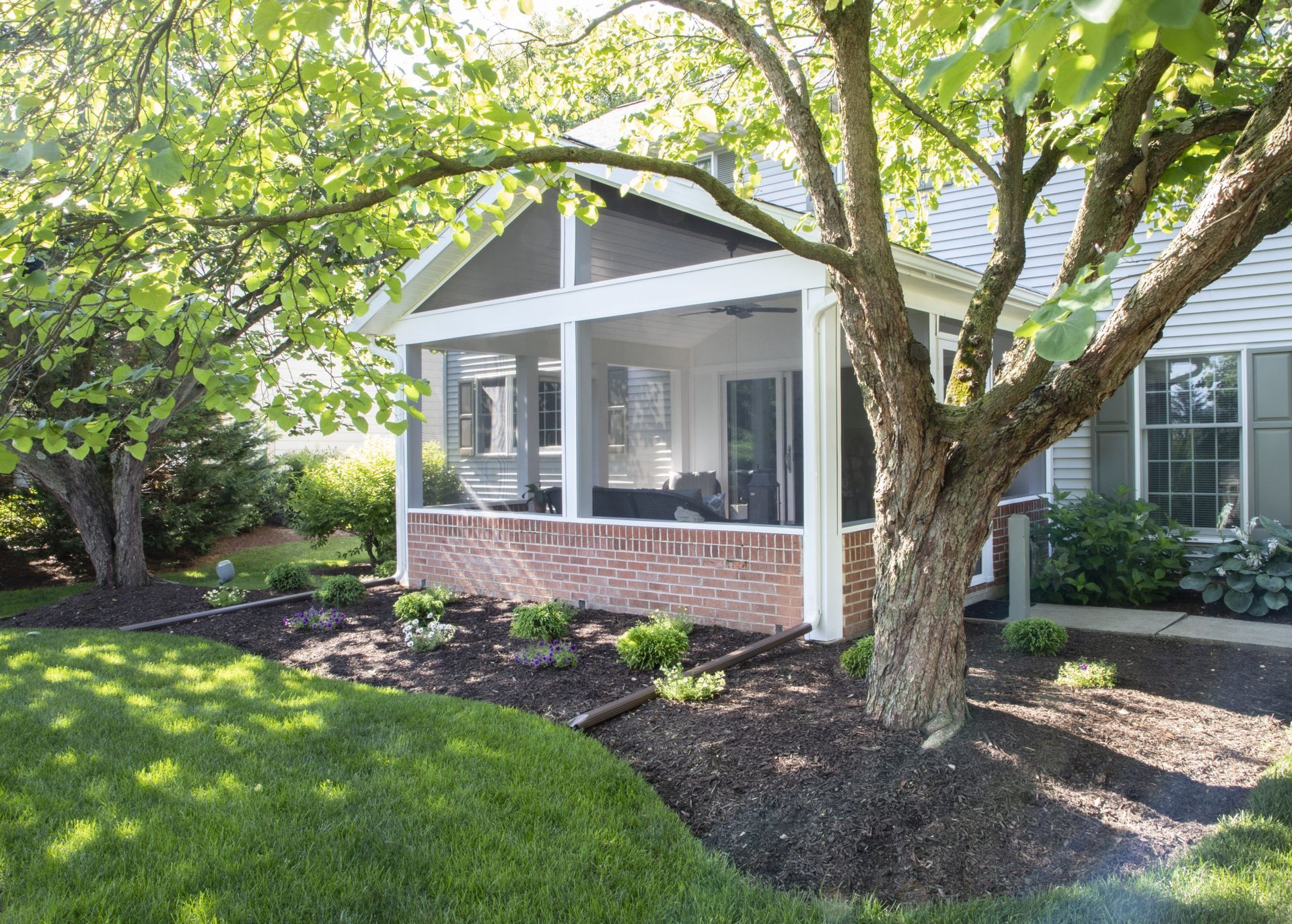 A screened in porch with a tree in front of it
