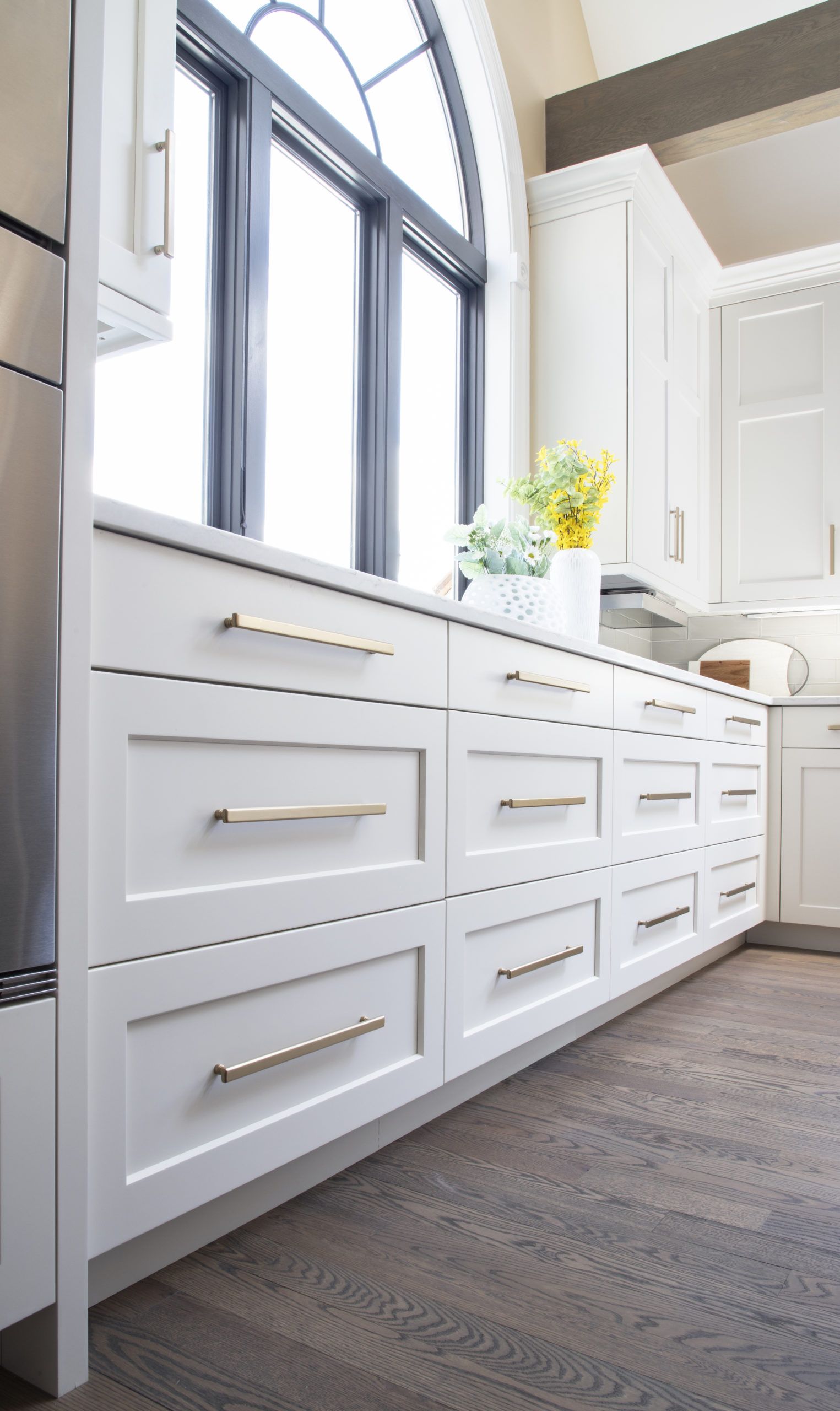 A kitchen with white cabinets and stainless steel appliances and a large window.
