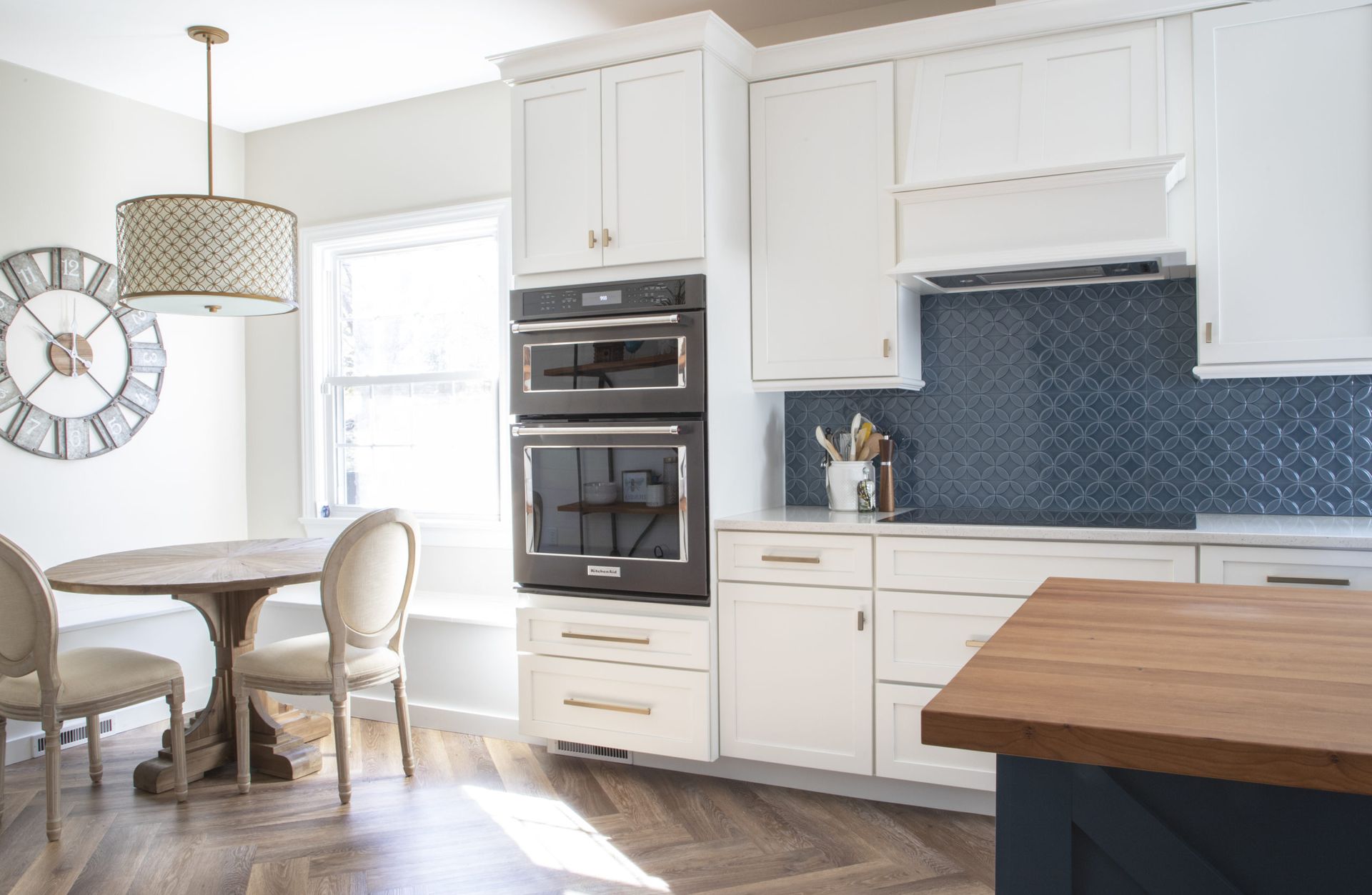 A kitchen with white cabinets , black appliances , a table and chairs.
