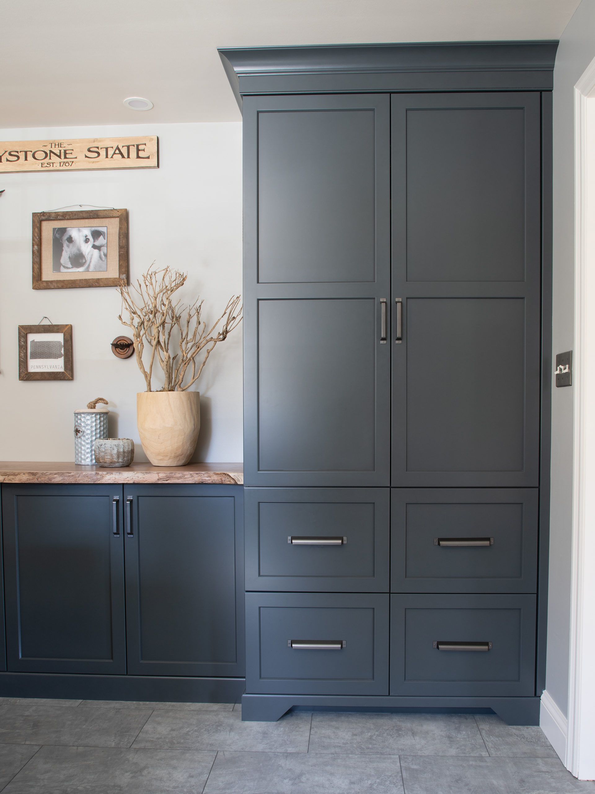 A kitchen with blue cabinets and drawers and a vase of flowers on the counter.