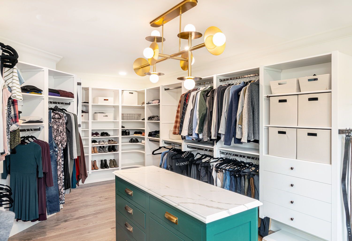 A walk in closet filled with lots of clothes and a large island.
