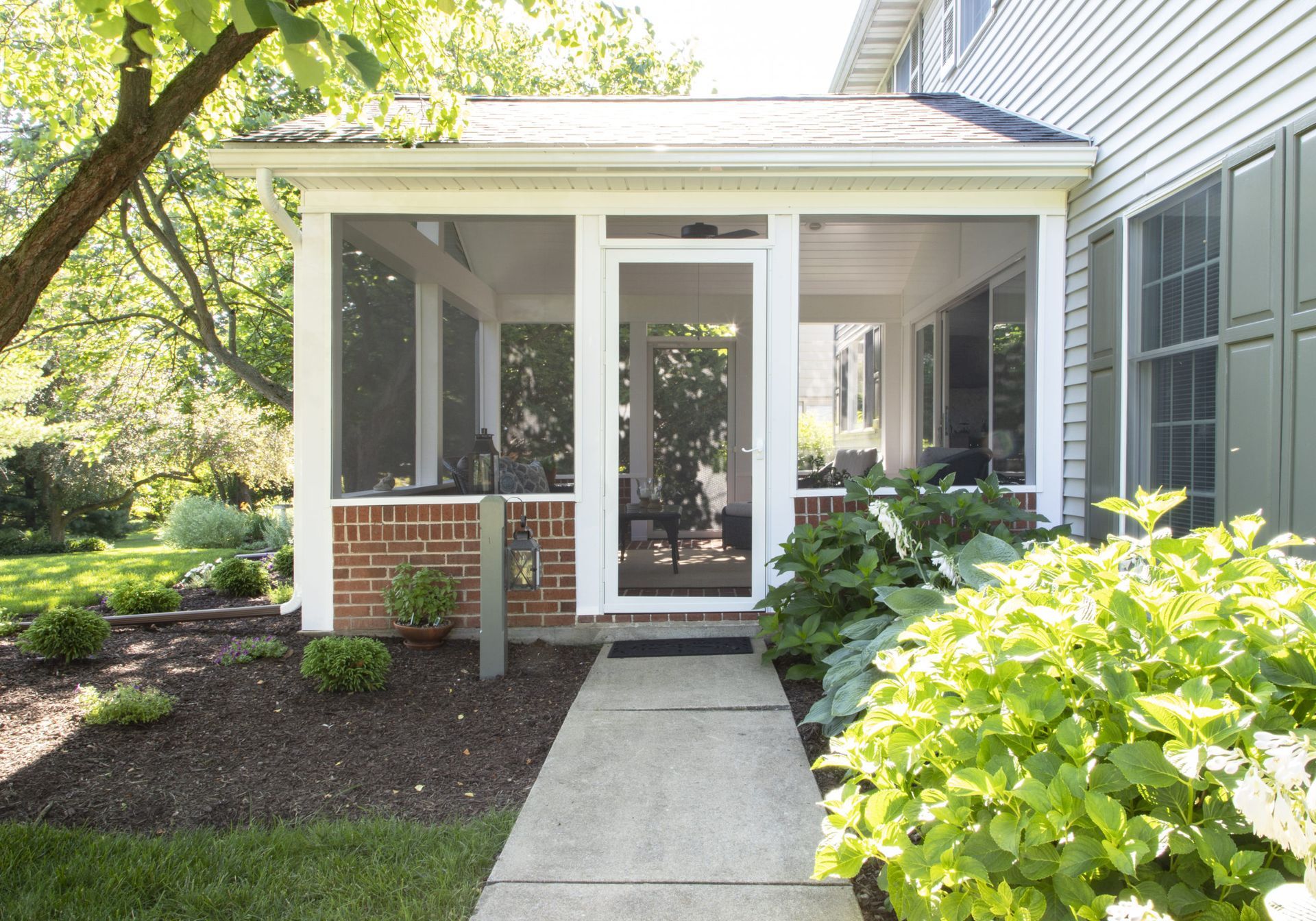 A screened in porch with a walkway leading to it