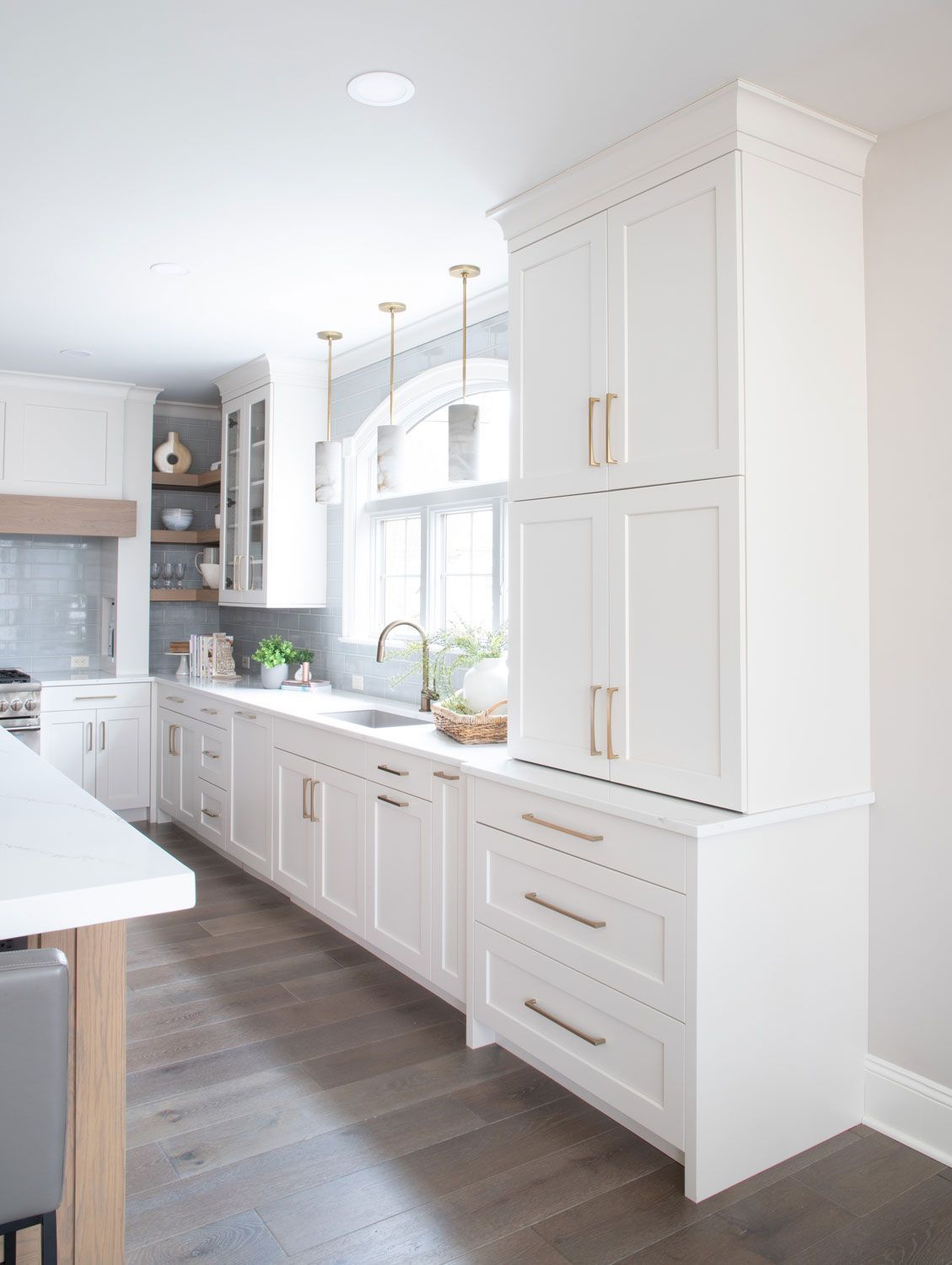 A kitchen with white cabinets , a sink , and a window.