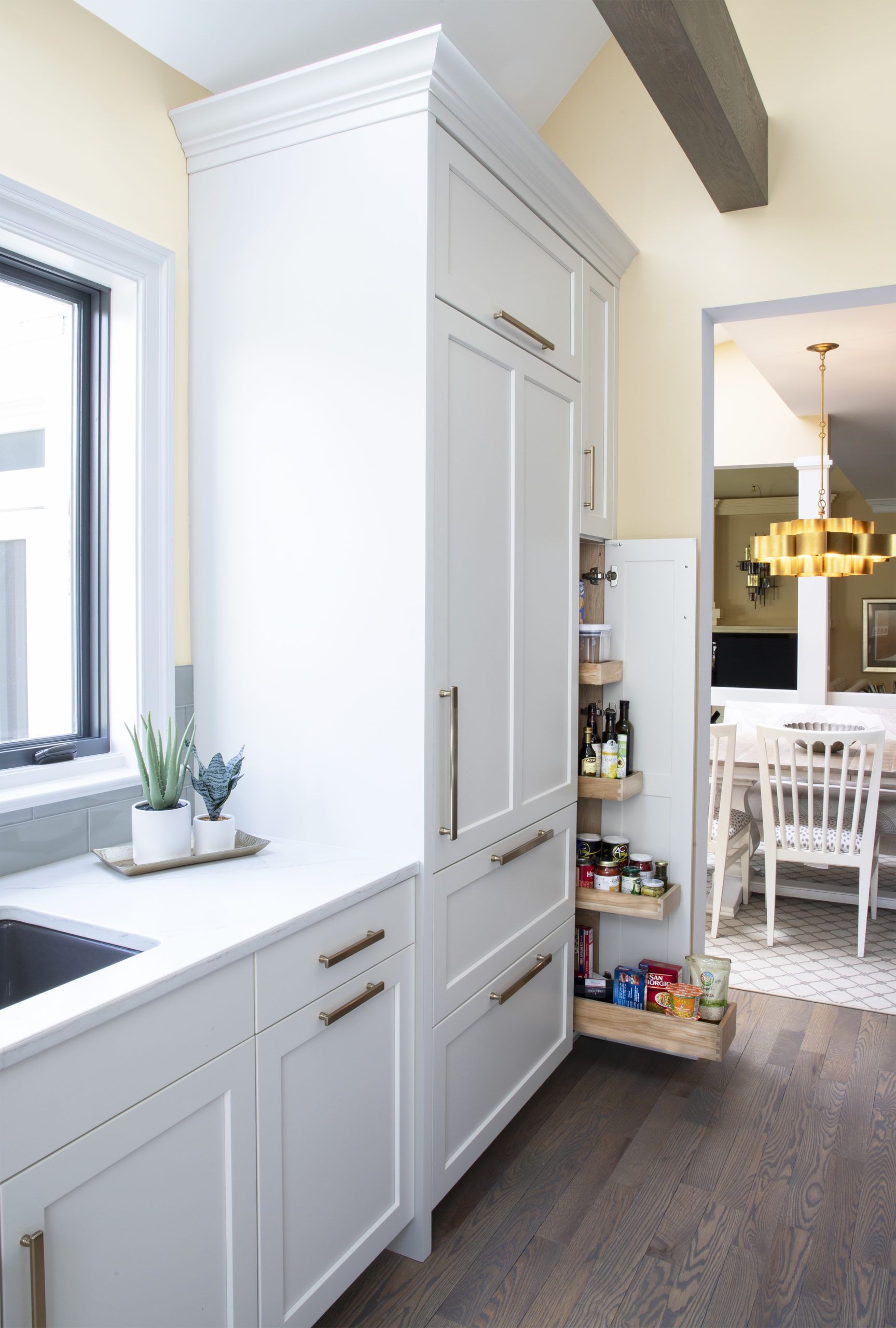 A kitchen with white cabinets and a pull out pantry