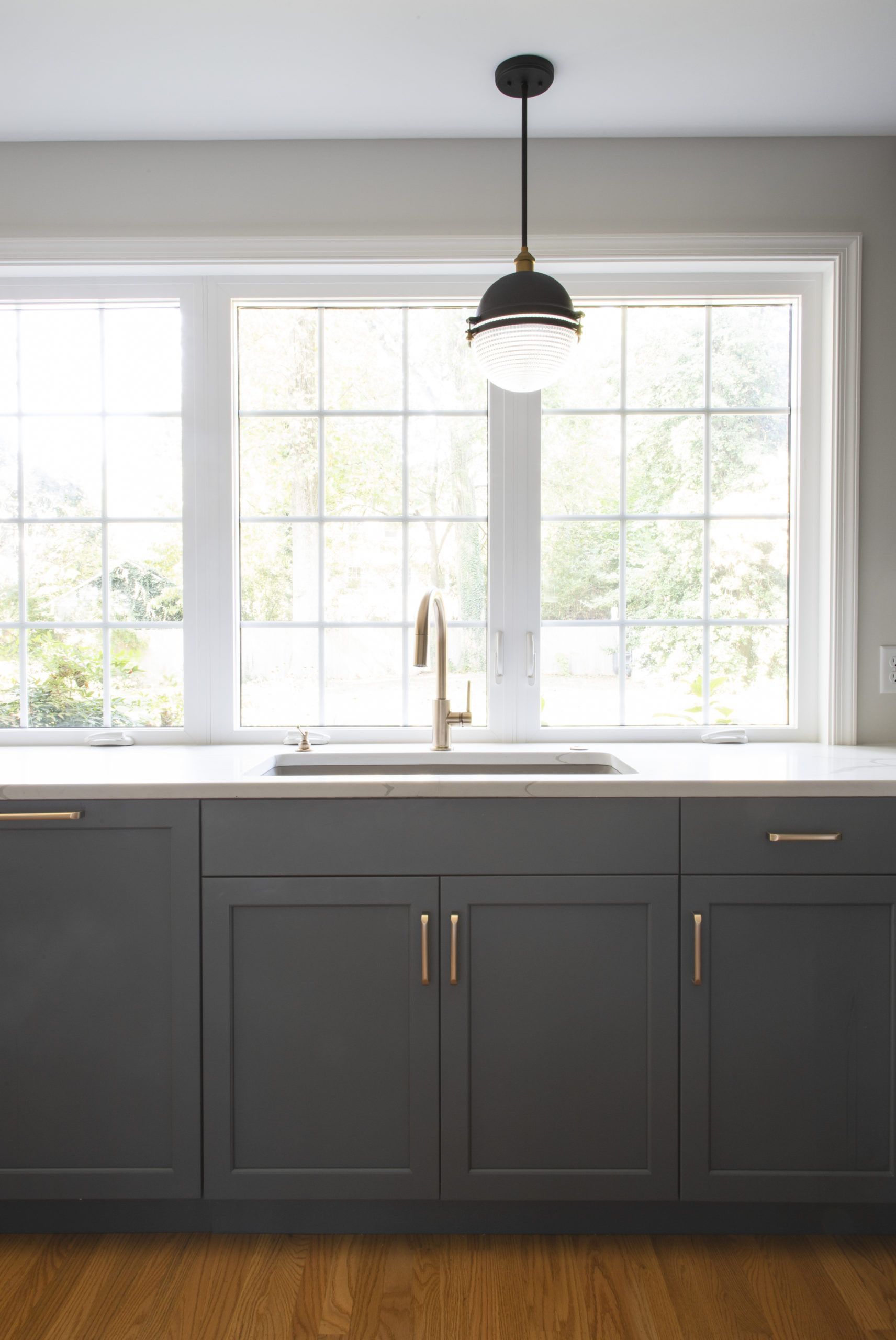 A kitchen with a sink , cabinets , and a window.
