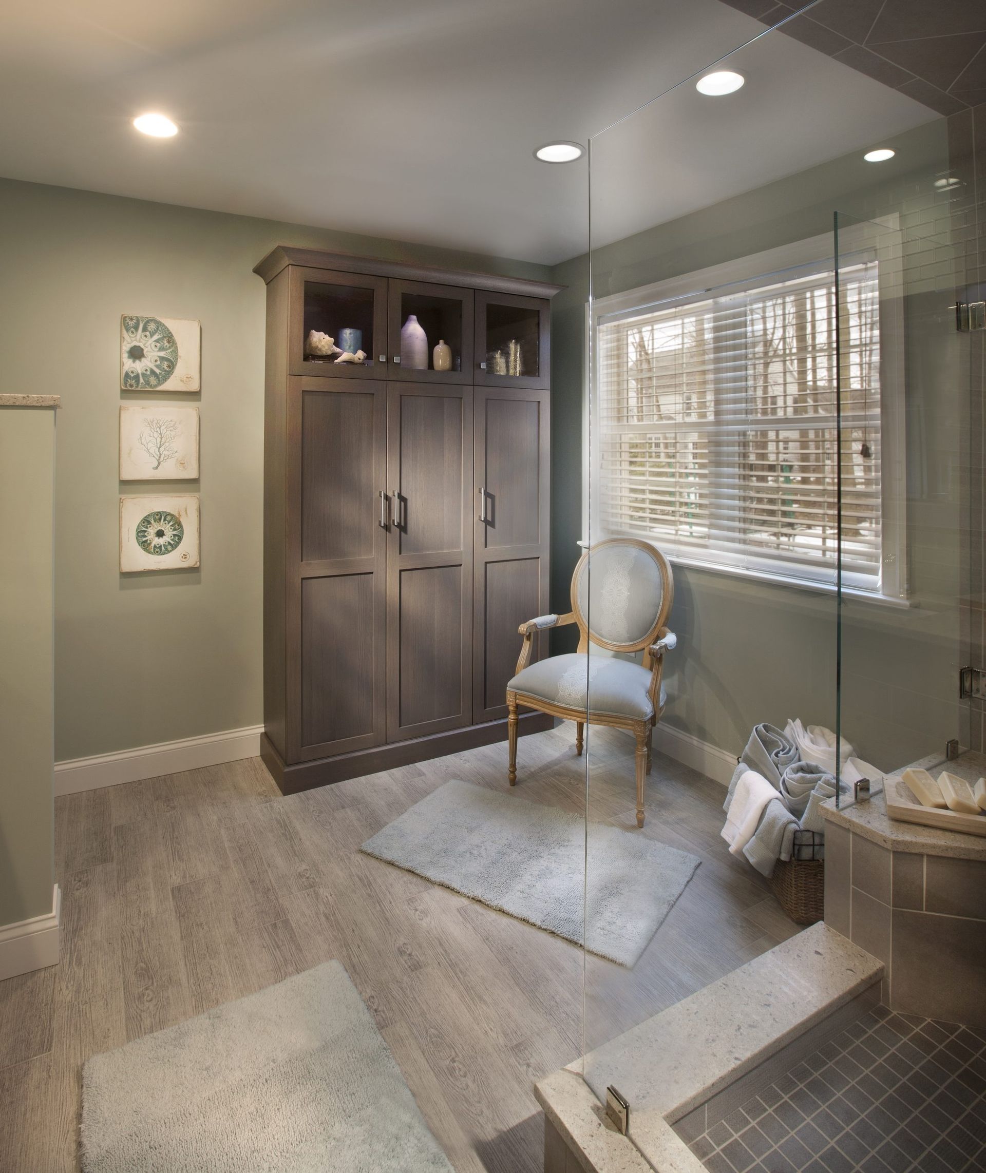 A bathroom with a chair and a walk in shower