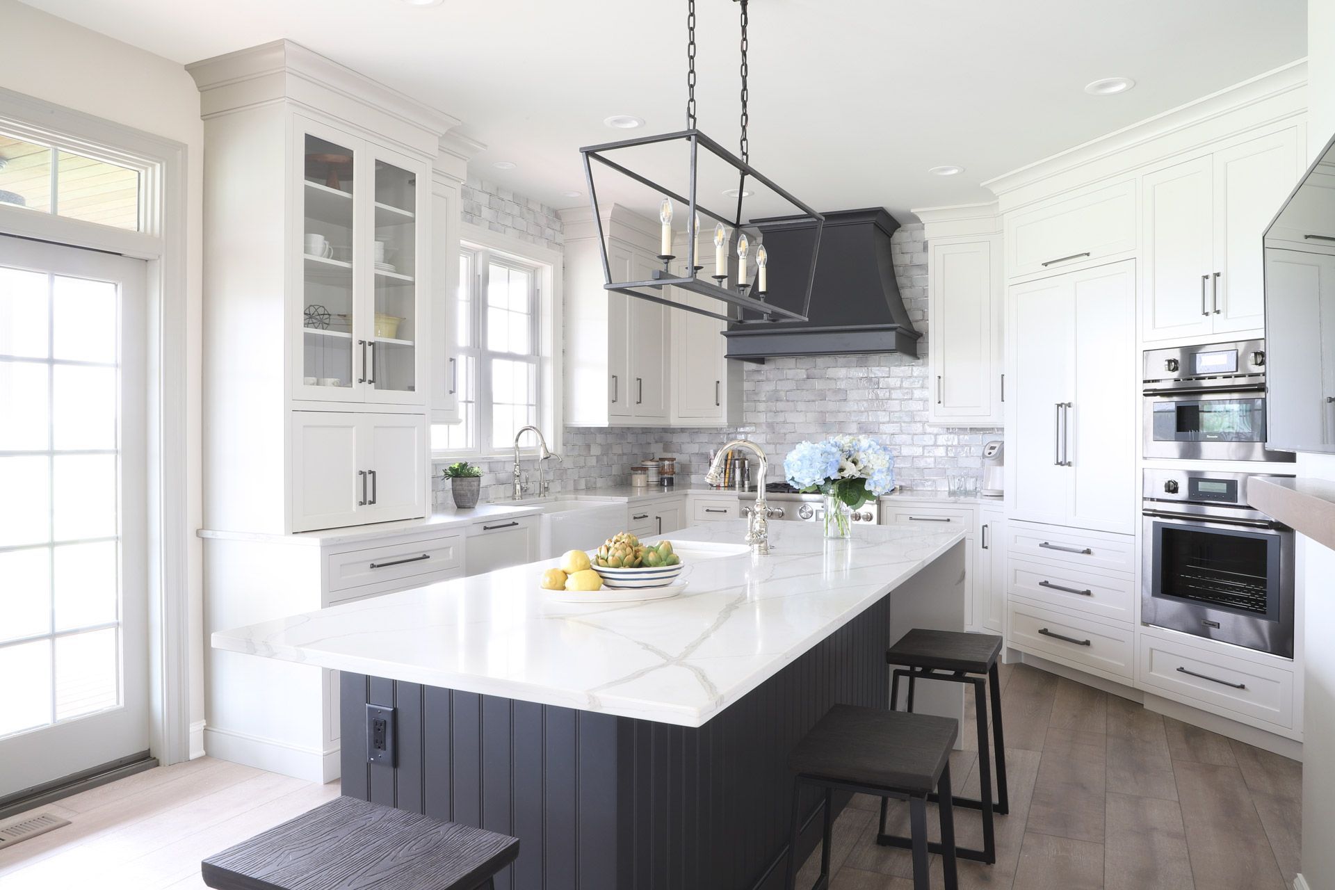 White kitchen with a copper range hood, black countertops, and a patterned rug.